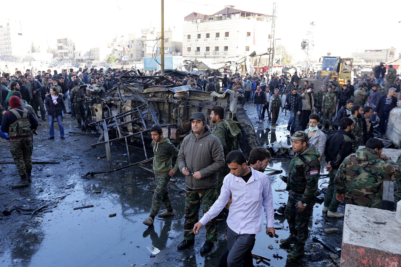 Syrian people and soldiers gather at the site of a bombing in Damascus on Jan 31, 2016.