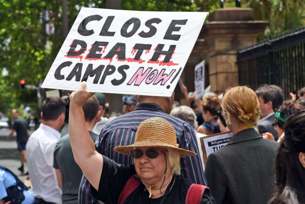 A pro-refugee protester holds up a placard outside the Transfield Services annual general meeting in Sydney on Oct 28, 2015. Transfield runs Australia's offshore detention centres on the Pacific island of Nauru and Papua New Guinea's Manus Island. 