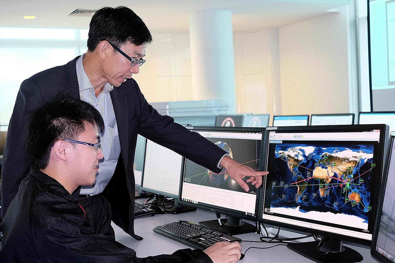 Prof Low showing the flight paths of the six NTU satellites currently in orbit to research fellow Lee Guo Xiong.