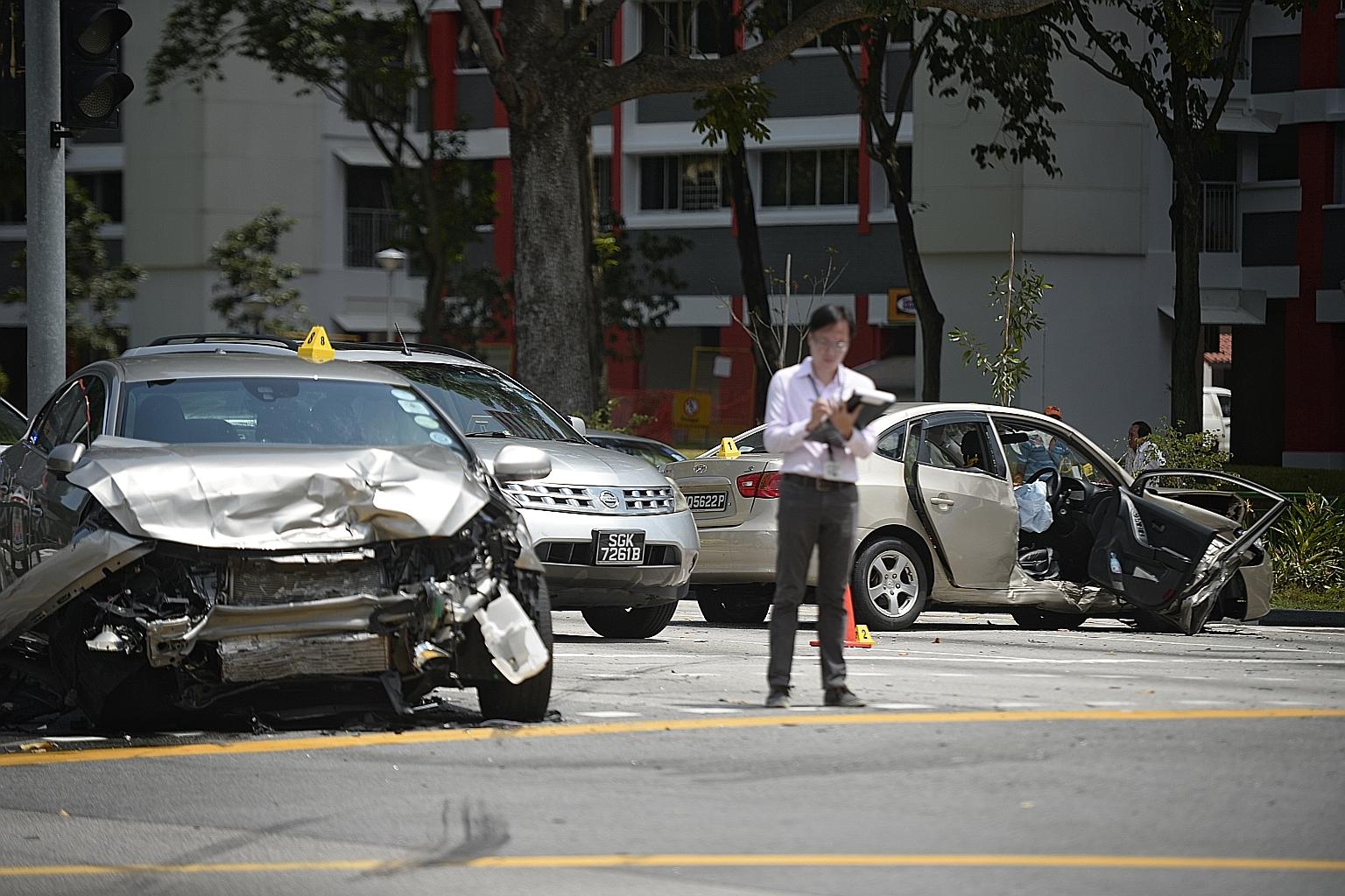 A police investigator taking notes at the scene of the crash involving a Volvo (left), a Hyundai (right) and a taxi yesterday.