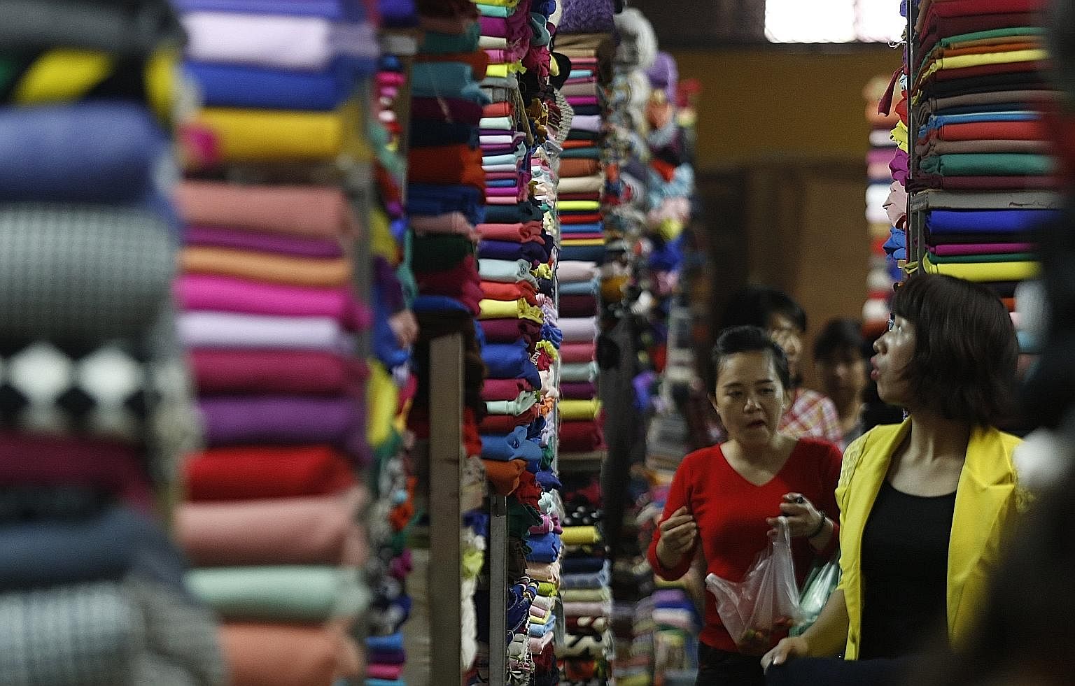 Customers walking among rows of fabric on display at a market in Hanoi. Despite Vietnam's tremendous progress, the nation remains in a fragile state with one-third of its 30 million people being vulnerable to falling back into poverty.