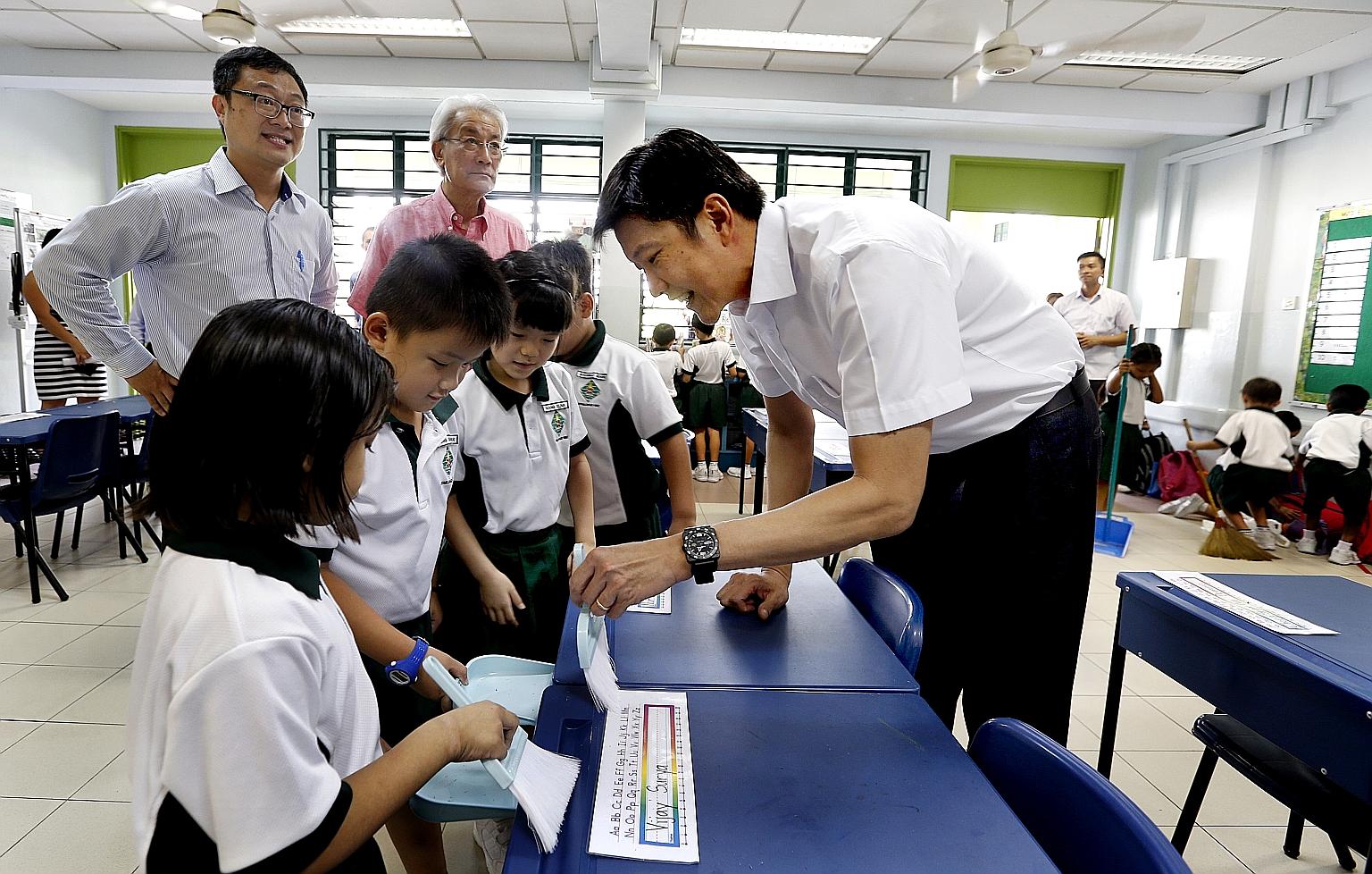 Acting Minister for Education (Schools) Ng Chee Meng (far right) lending a hand to pupils in Xingnan Primary School as they cleaned their classroom yesterday, with Public Hygiene Council chairman Edward D'Silva (in pink shirt) and school principal Ch