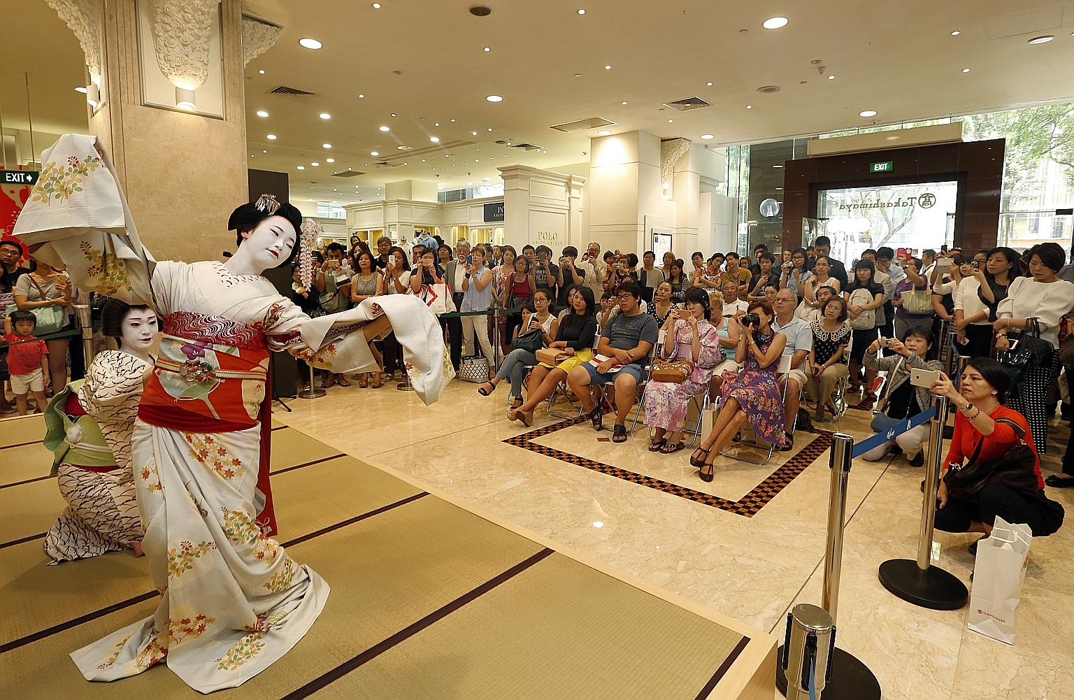 Performers from Kyoto doing a traditional duet dance for shoppers at Takashimaya department store yesterday, as part of the Kyoto Sakura celebration. The dancers are known as geiko (far left) and maiko - as geishas are known in Kyoto. The maiko is an