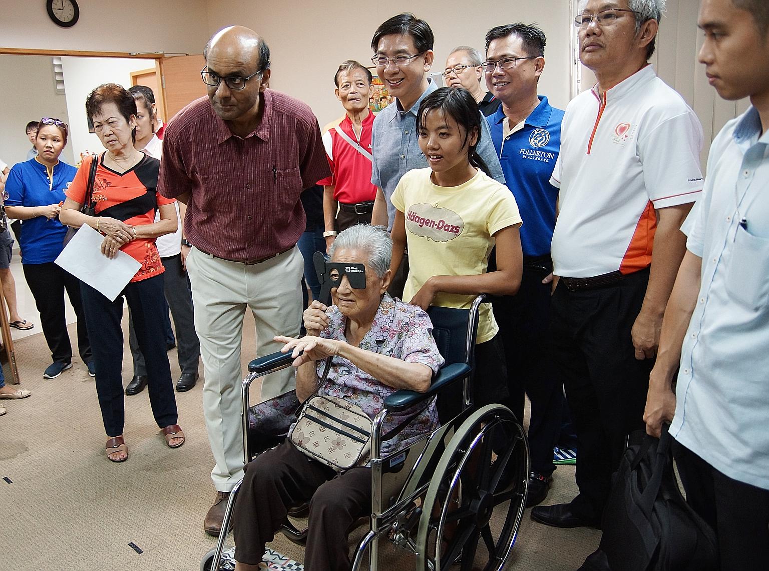 Deputy Prime Minister Tharman Shanmugaratnam (in purple) visiting an eye screening station at yesterday's health carnival in Jurong. He noted that elderly residents were especially appreciative of such neighbourhood fairs as they bring health service