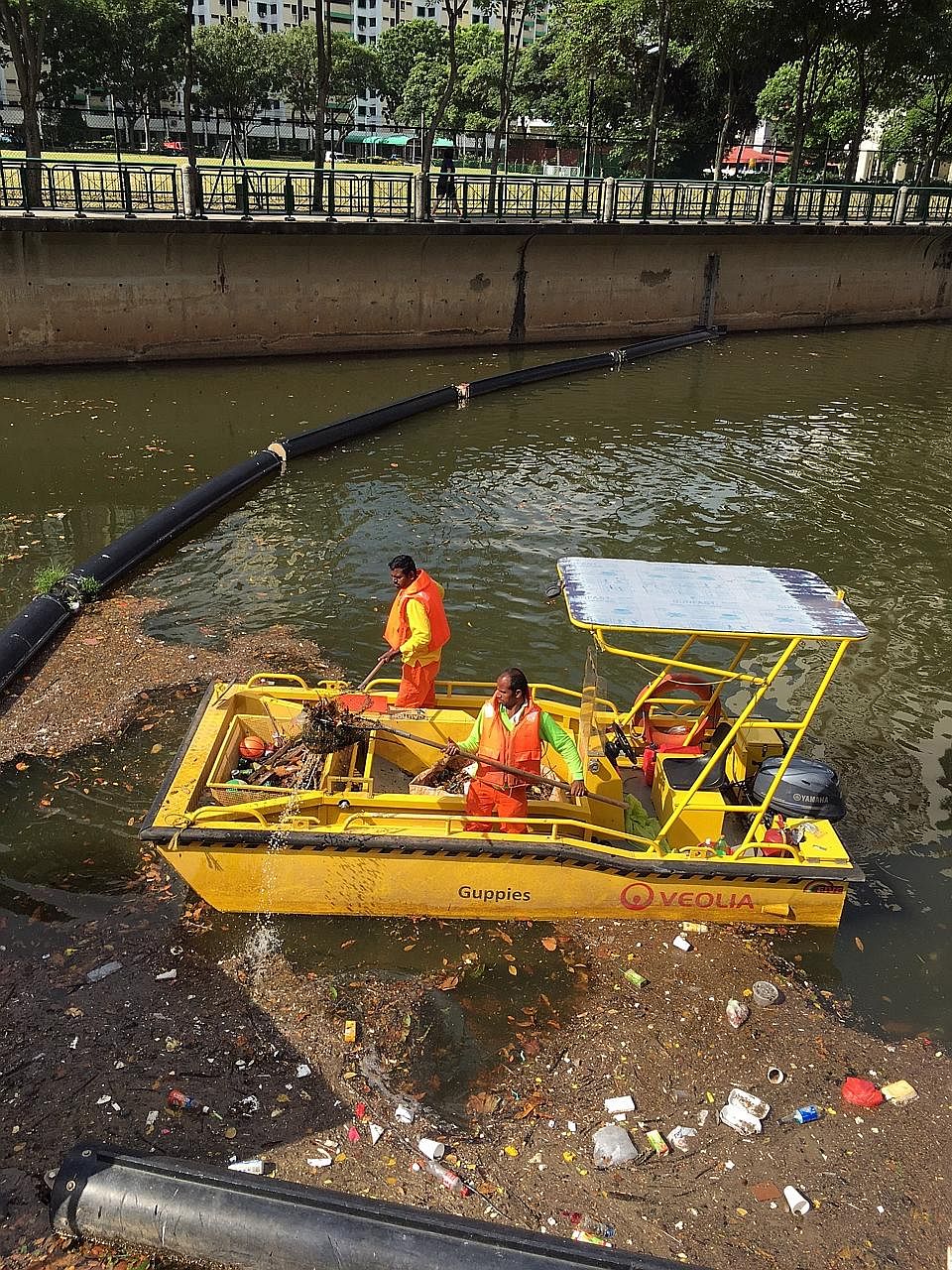 Workers cleaning up debris that was washed down Alexandra Canal, near Great World City, after a storm last month. Traps and float booms are placed at waterways to minimise litter flowing into the sea. Last year, the NEA collected about 920 tonnes of 