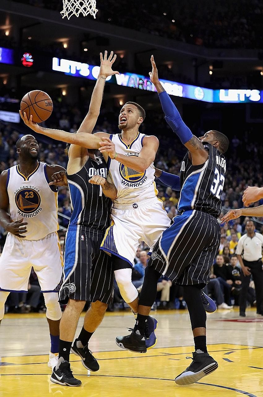 Stephen Curry of the Golden State Warriors (second from right) shoots after evading close marking from C. J. Watson (32) and Evan Fournier of the Orlando Magic on Monday. The Warriors won 119-113 to overtake the Chicago Bulls' record of 44 straight h