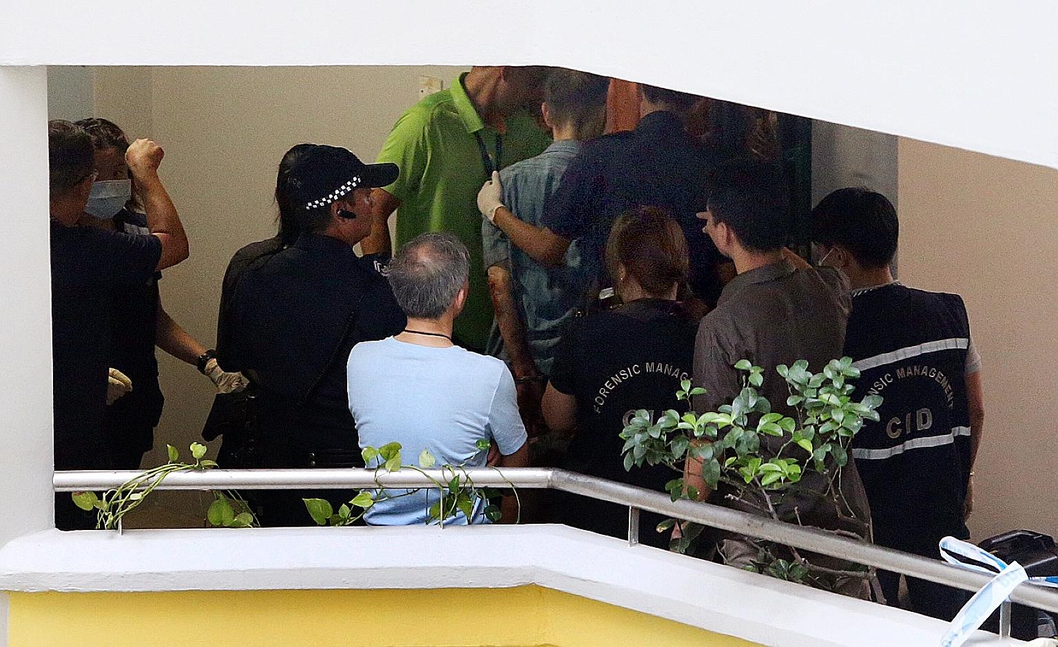 The victim's husband (centre) being led away in handcuffs by police at about 7.20pm.