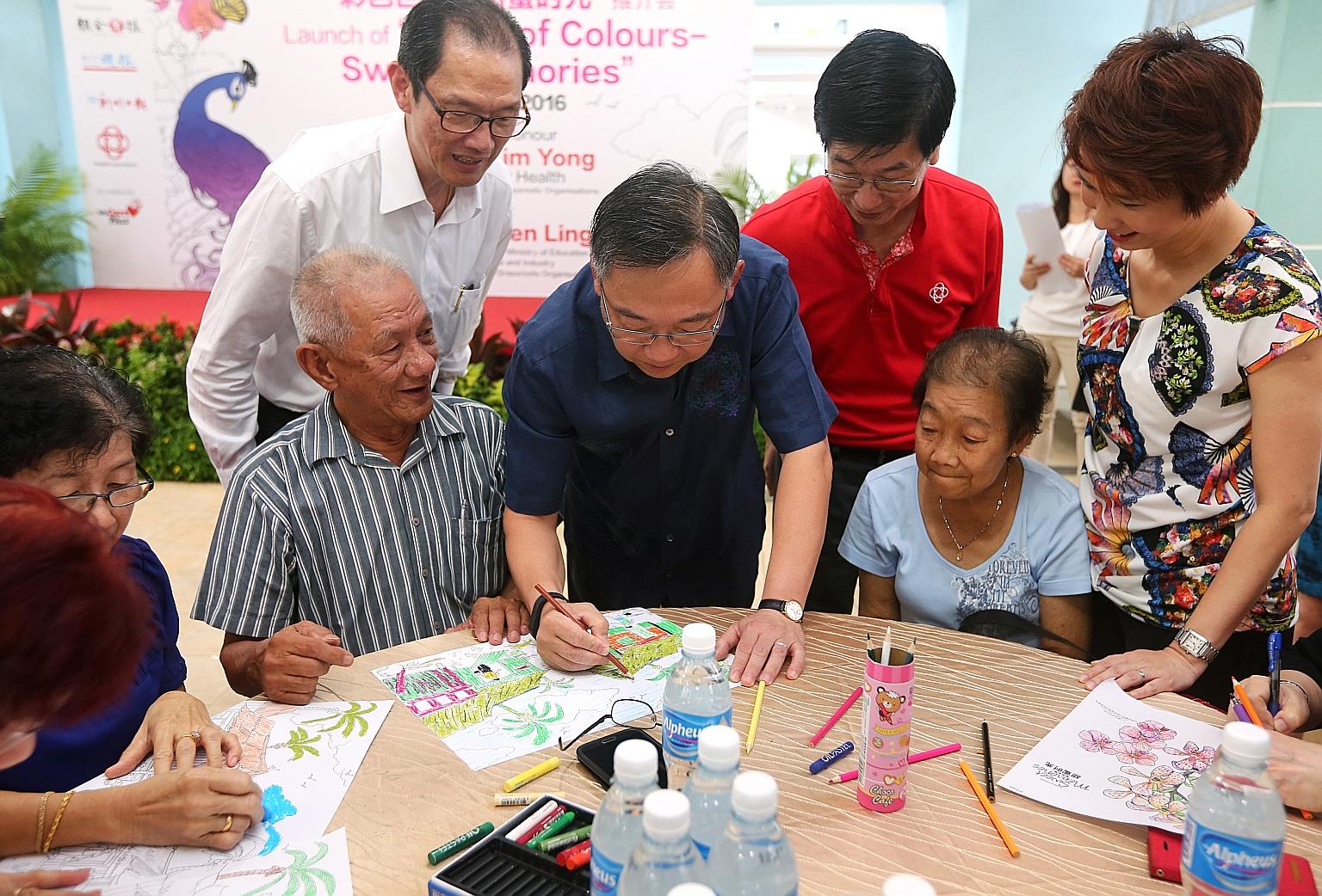 Mr Gan Kim Yong (centre) tries his hand at colouring with senior citizens at the launch of World Of Colours - Sweet Memories at Bukit Batok West yesterday. Looking on are (from left) Mr Seow Choke Meng, business consultant of SPH's Chinese Media Grou