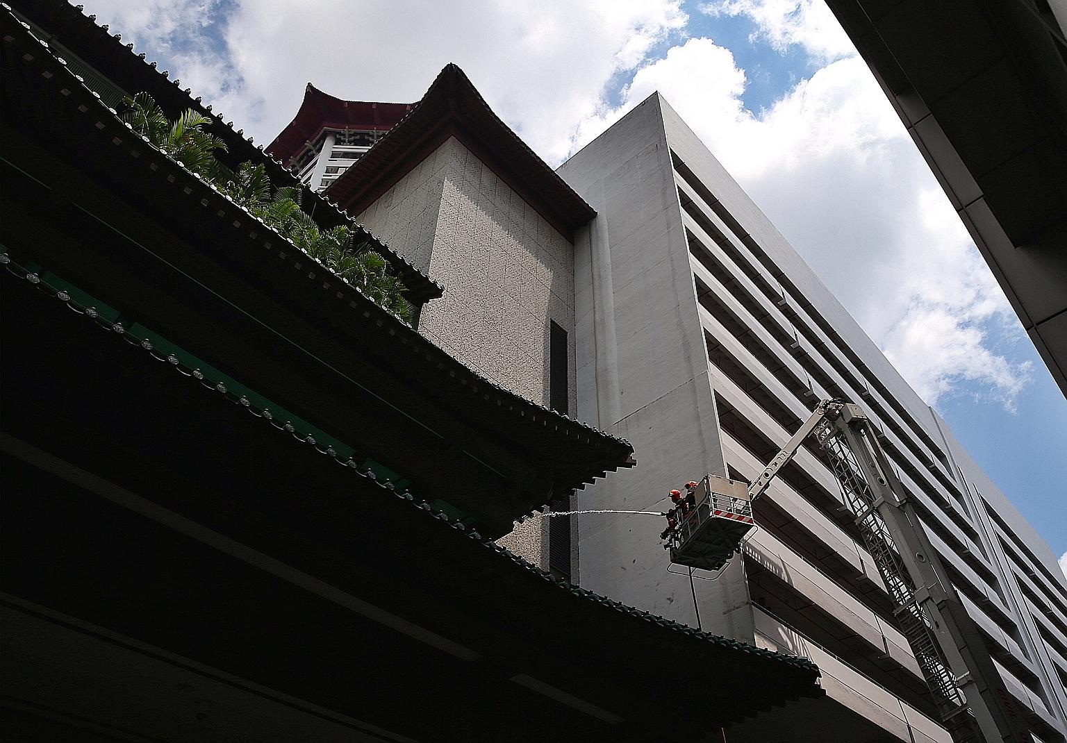 SCDF officers hosing down the affected area after a fire broke out at Tang Plaza yesterday at around 9am. No one was injured in the blaze.