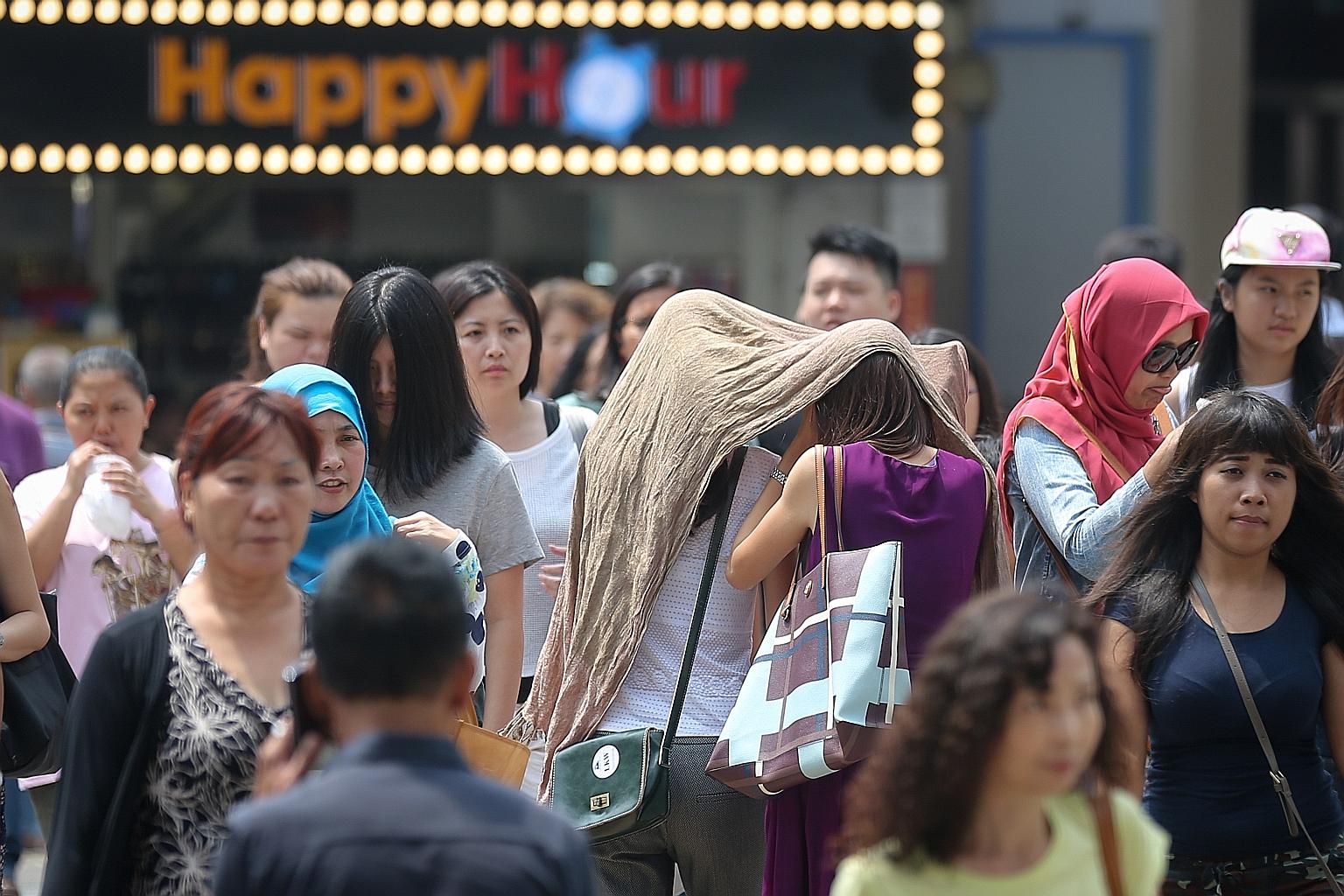 Pedestrians in Victoria Street shielding themselves from the blazing hot sun yesterday. The Education Ministry has sent a circular reminding schools to be mindful of the well-being of teachers and students, as they engage in outdoor activities. The H