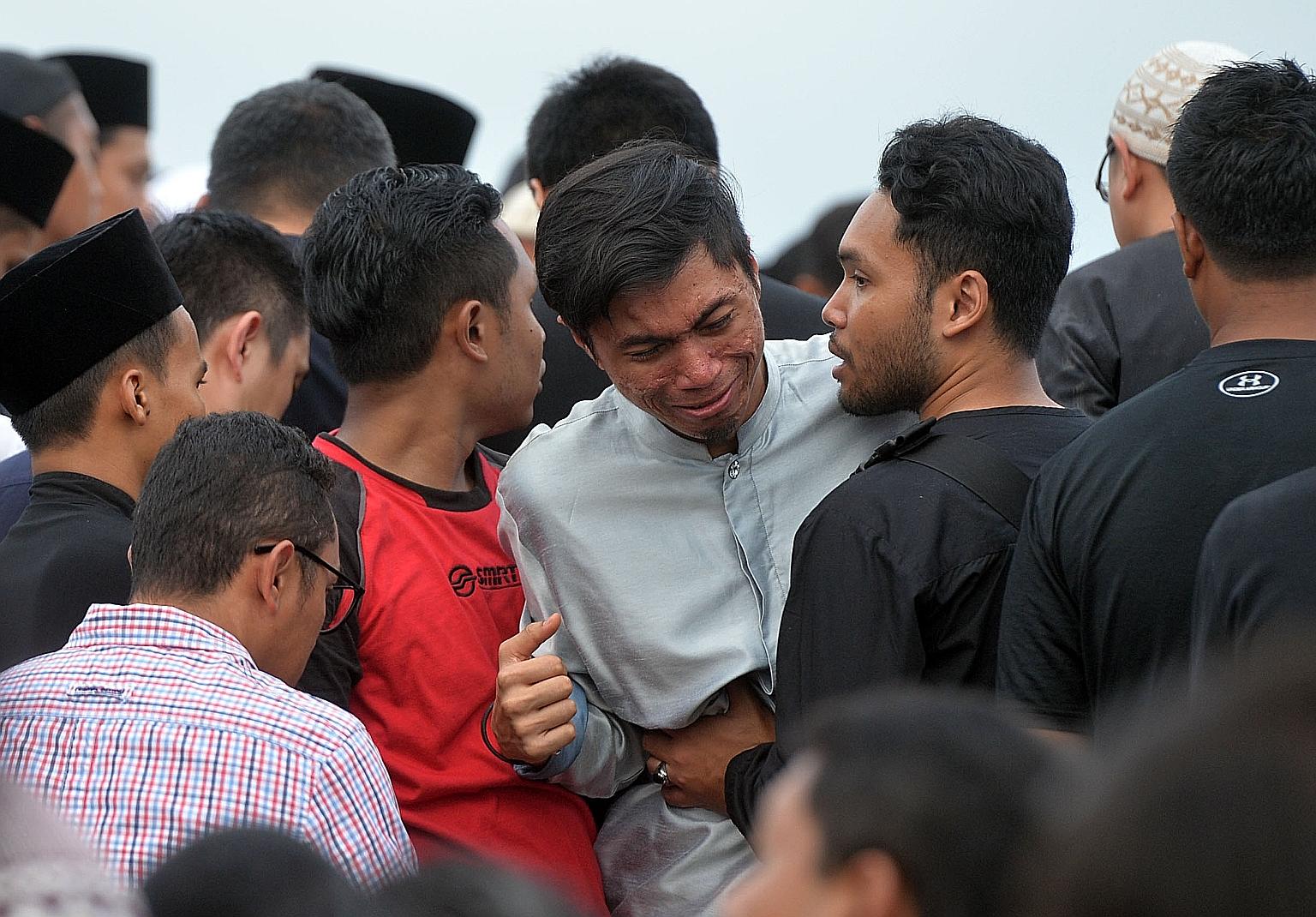 Mr Hatin (centre) grieving at the burial of his two SMRT colleagues at the Muslim cemetery in Lim Chu Kang yesterday.