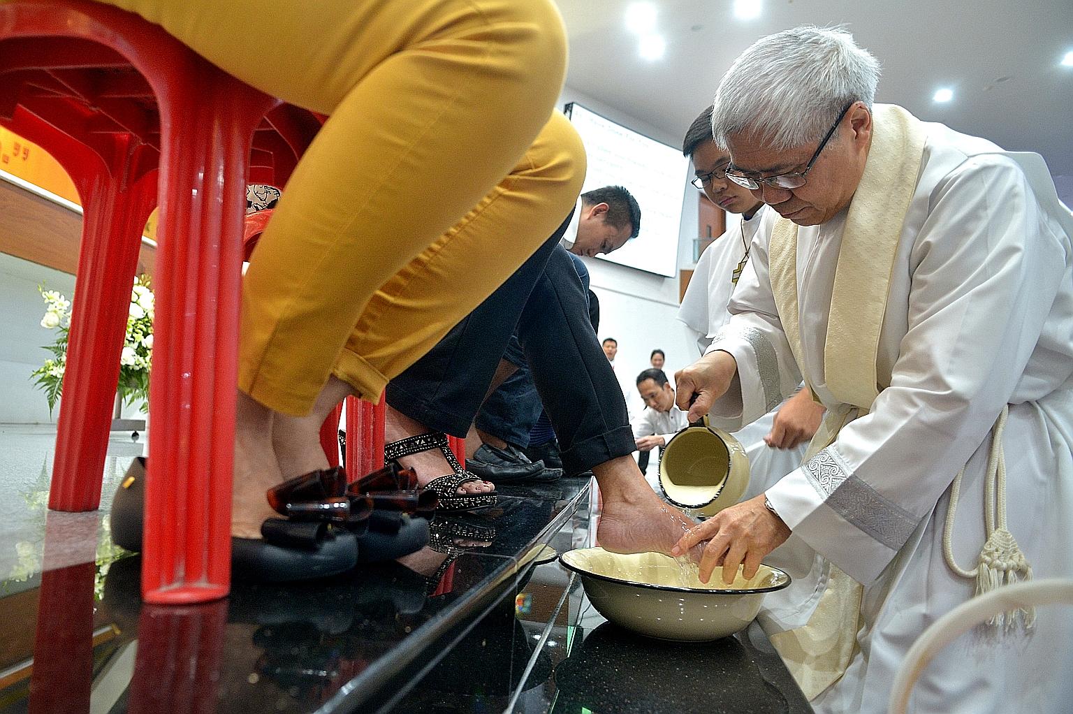 Catholic Archbishop William Goh washing the feet of one of 12 parishioners at the Church of the Holy Cross, as part of its annual Maundy Thursday mass. Half of them were women, a first this year following a new ruling issued by Pope Francis in Januar