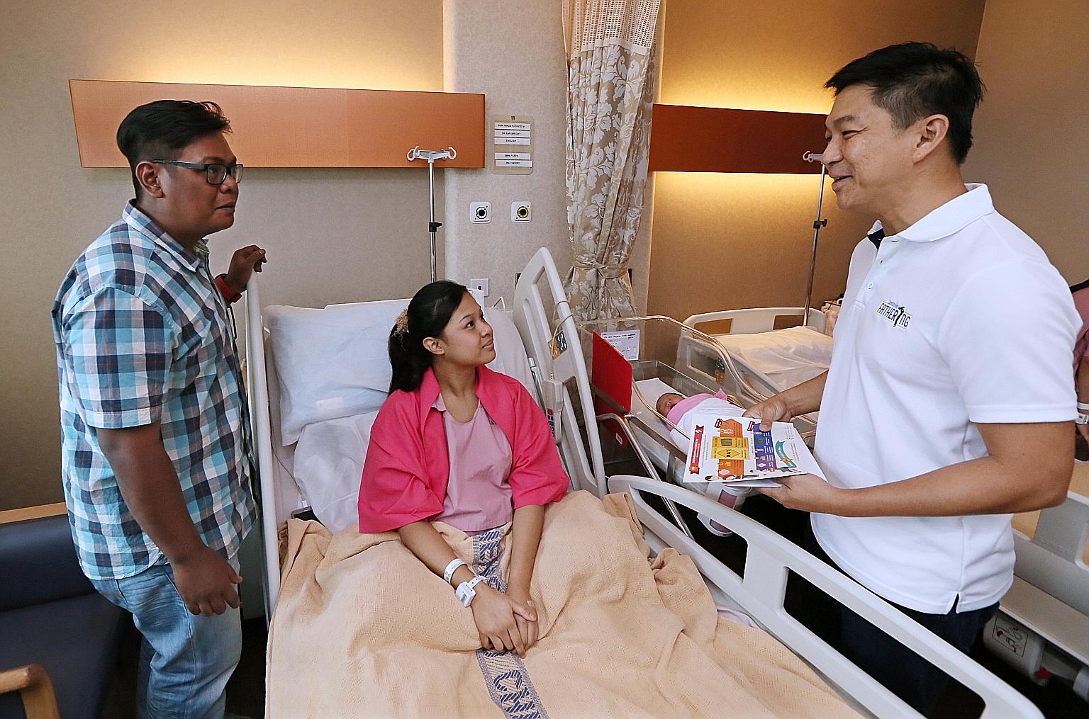 Mr Tan explaining the Child Development Account First Step grant to Mr Mohamad Sopian bin Hairi, 30, and his wife Seri Hirdayu, 25, whose third child, Liya Zafirah, was born on Thursday.
