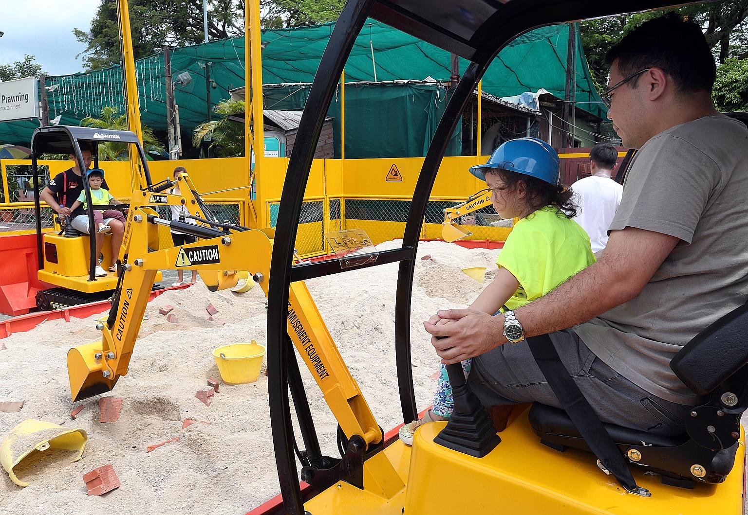 Mr Victor Khoo (right), 37, operating an excavator at Diggersite with his daughter Sophie, two. The owner, Mr Lim, hopes that his enterprise will improve perceptions of blue-collar jobs.