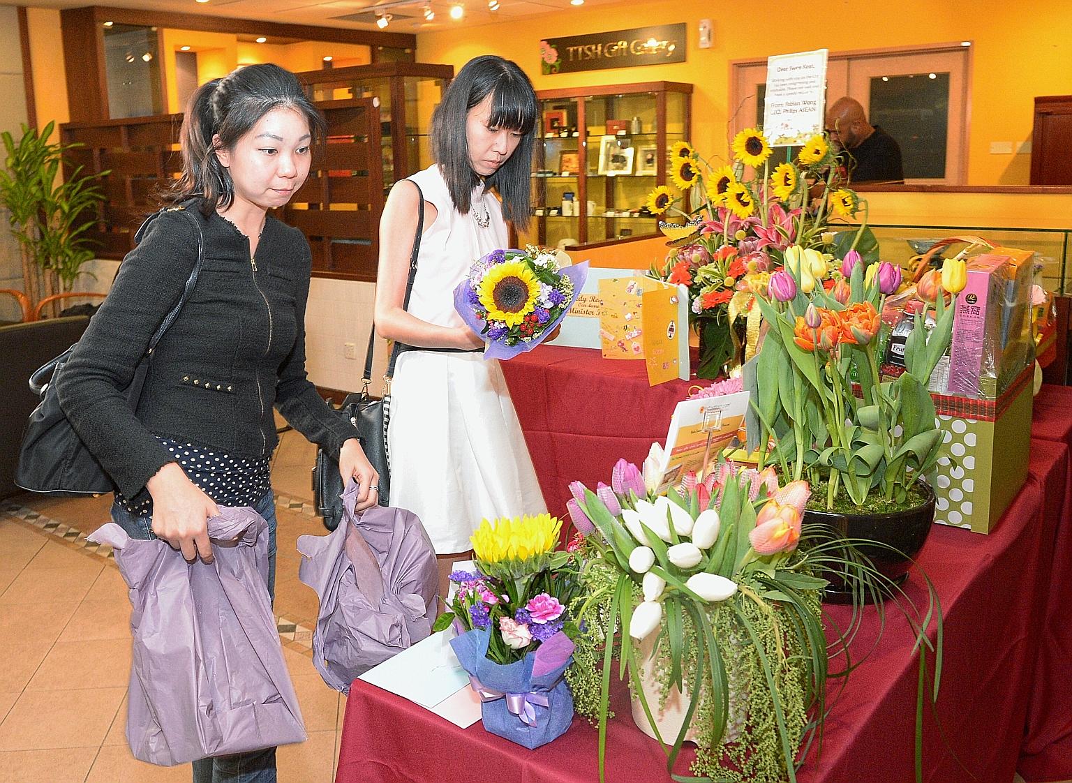 Tampines residents Kathy Goh (left), 31, and Janessa Thng, 30, leaving flowers at Tan Tock Seng Hospital, where Mr Heng remains in the intensive care unit. They were among many who visited the hospital yesterday to place get-well cards, flowers and g