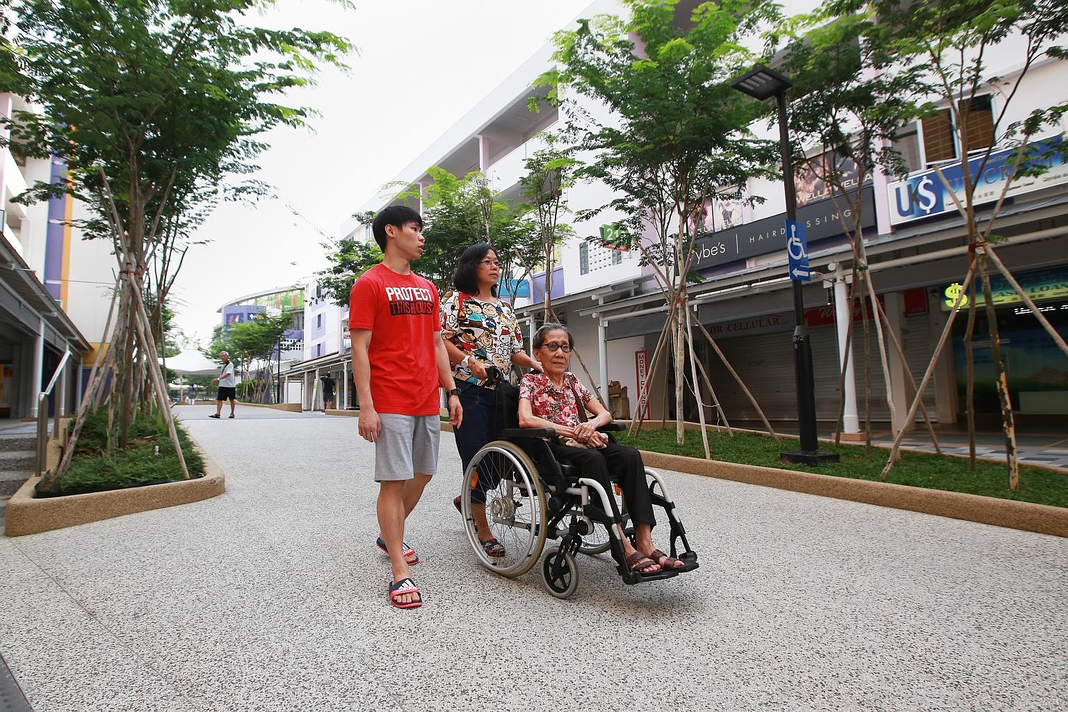 More ramps and signs installed after Bedok's upgrading works make it easier for wheelchair users like Madam Yeo, 77, seen here with her daughter Cheng See and grandson Kang Rui Jie, 21. The upgrades are part of the Housing Board's Remaking Our Heartl