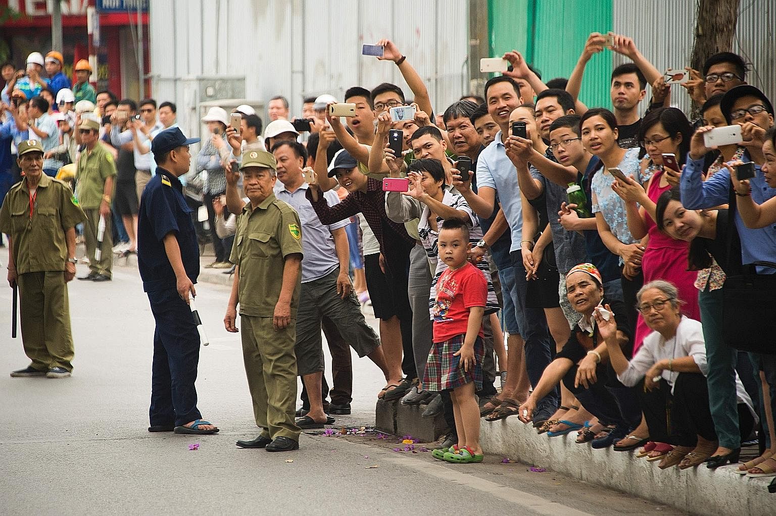 Vietnamese people taking pictures as Mr Obama's motorcade drove past in Hanoi yesterday. The US leader's three-day trip to Vietnam is part of his administration's strategic "rebalance" to Asia. Mr Obama and Ms Nguyen Thi Kim Ngan, chairman of the Vie
