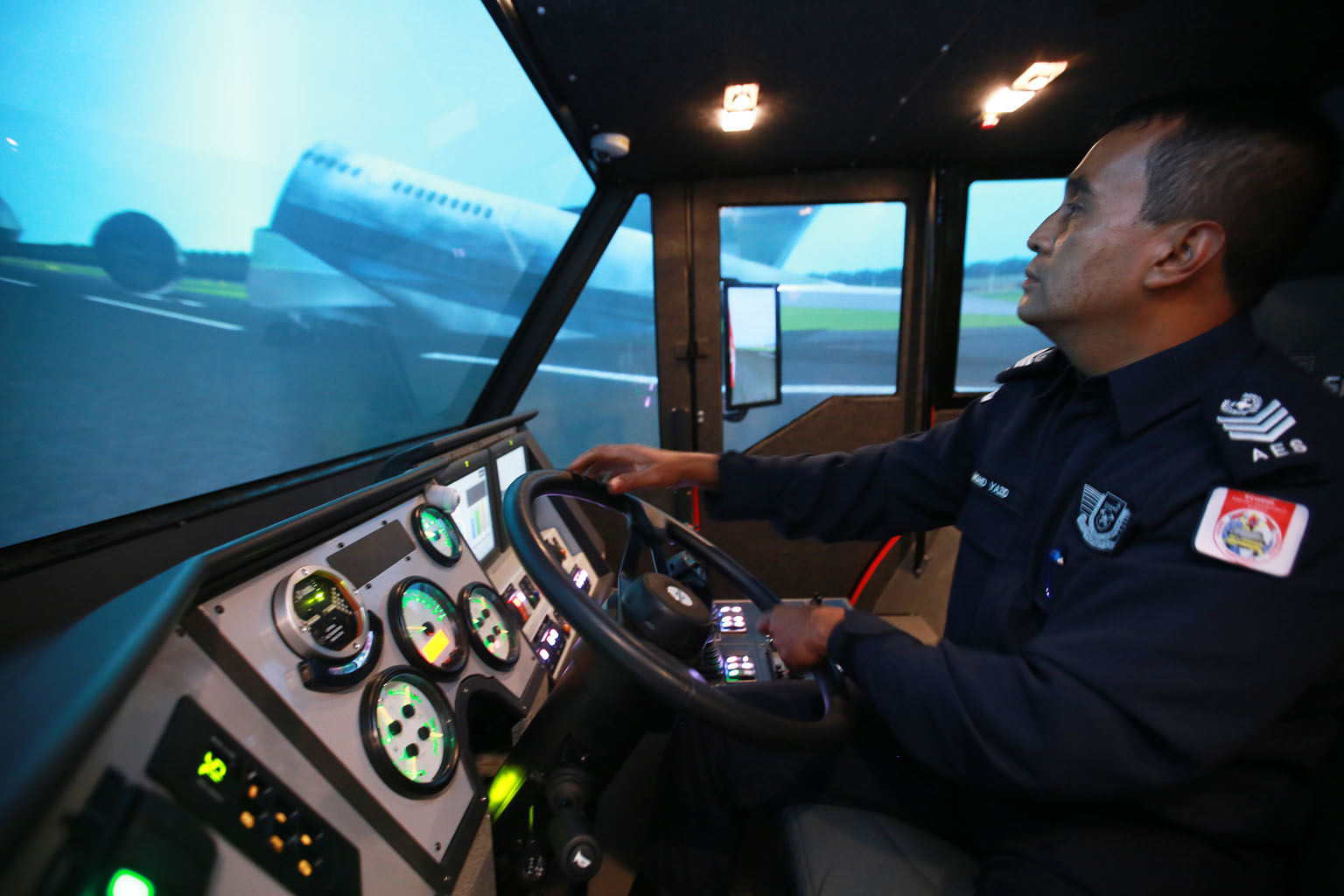 Airport Emergency Services Officer Mohd Yazid, 46, demonstrating how the simulator is used to train workers who drive special vehicles called foam tenders, which use foam and water to put out fires at the airport. 