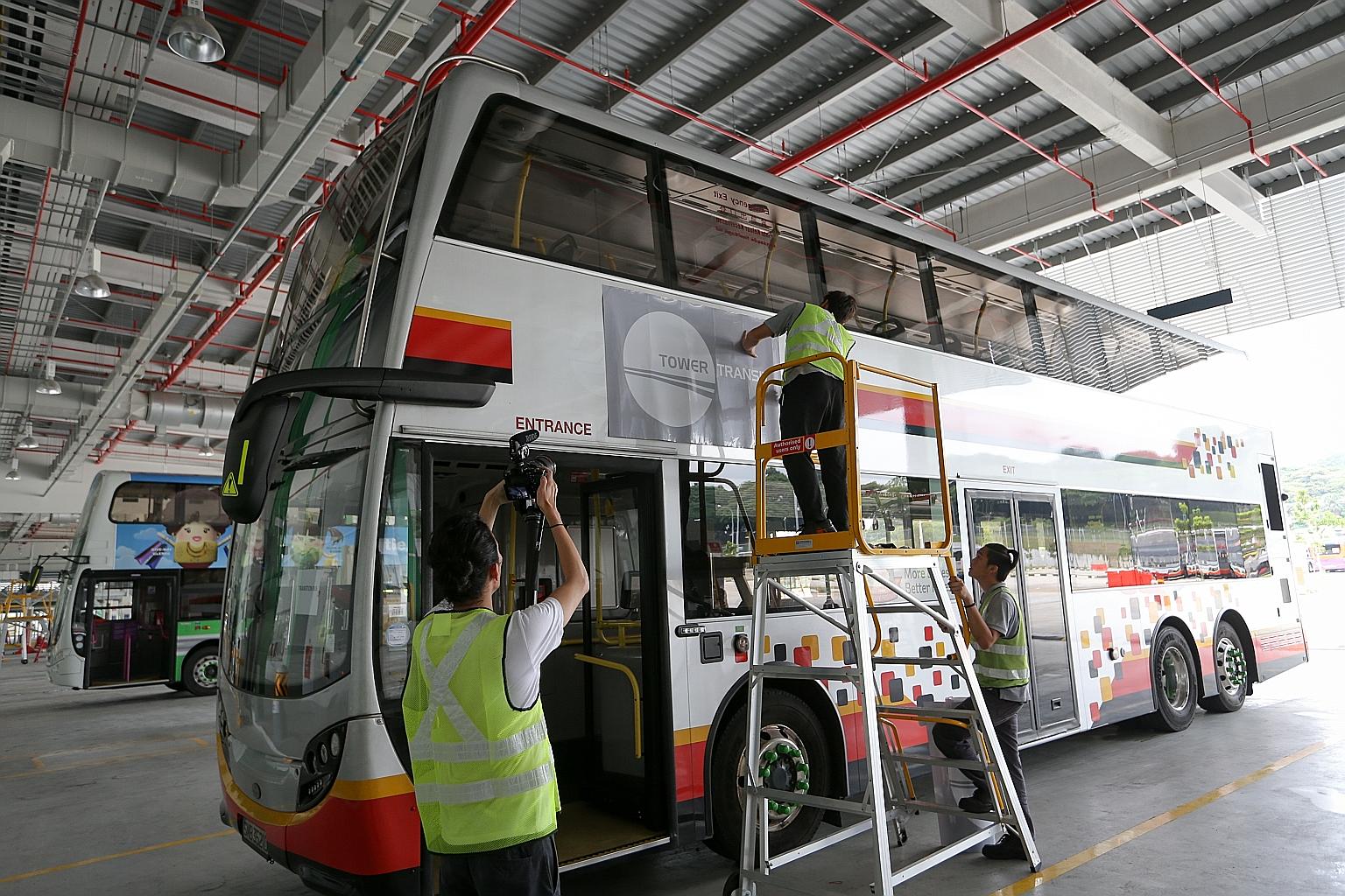 A Tower Transit logo being pasted onto an SMRT bus. The new bus operator is taking over more than 90 buses from SMRT as it launches the first nine of 26 services today. It will take over the remaining 17 services from SBS Transit in two batches next 