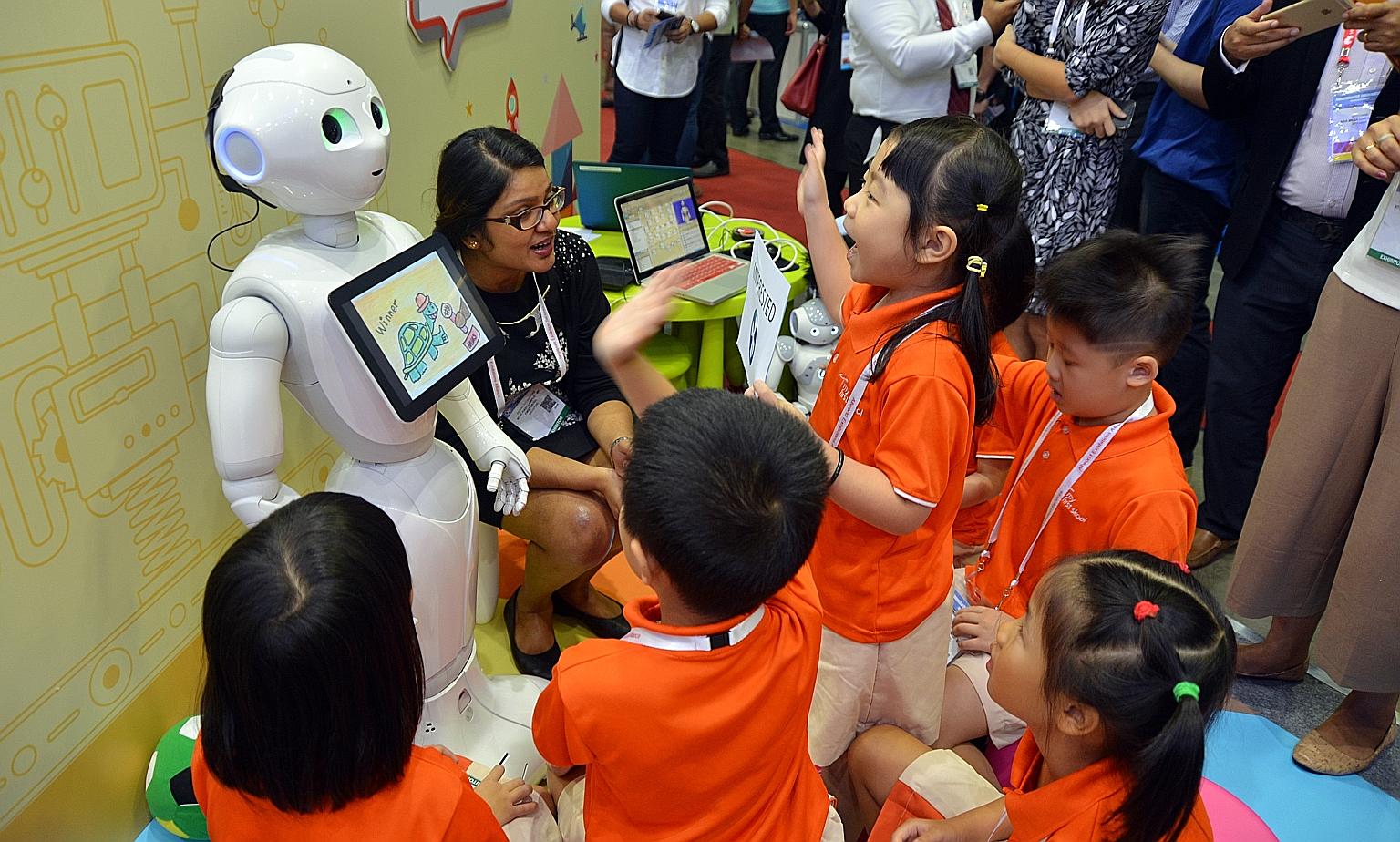 Children interacting with Pepper, one of the two humanoid robots on trial, at the Infocomm Media Business Exchange at Marina Bay Sands yesterday.