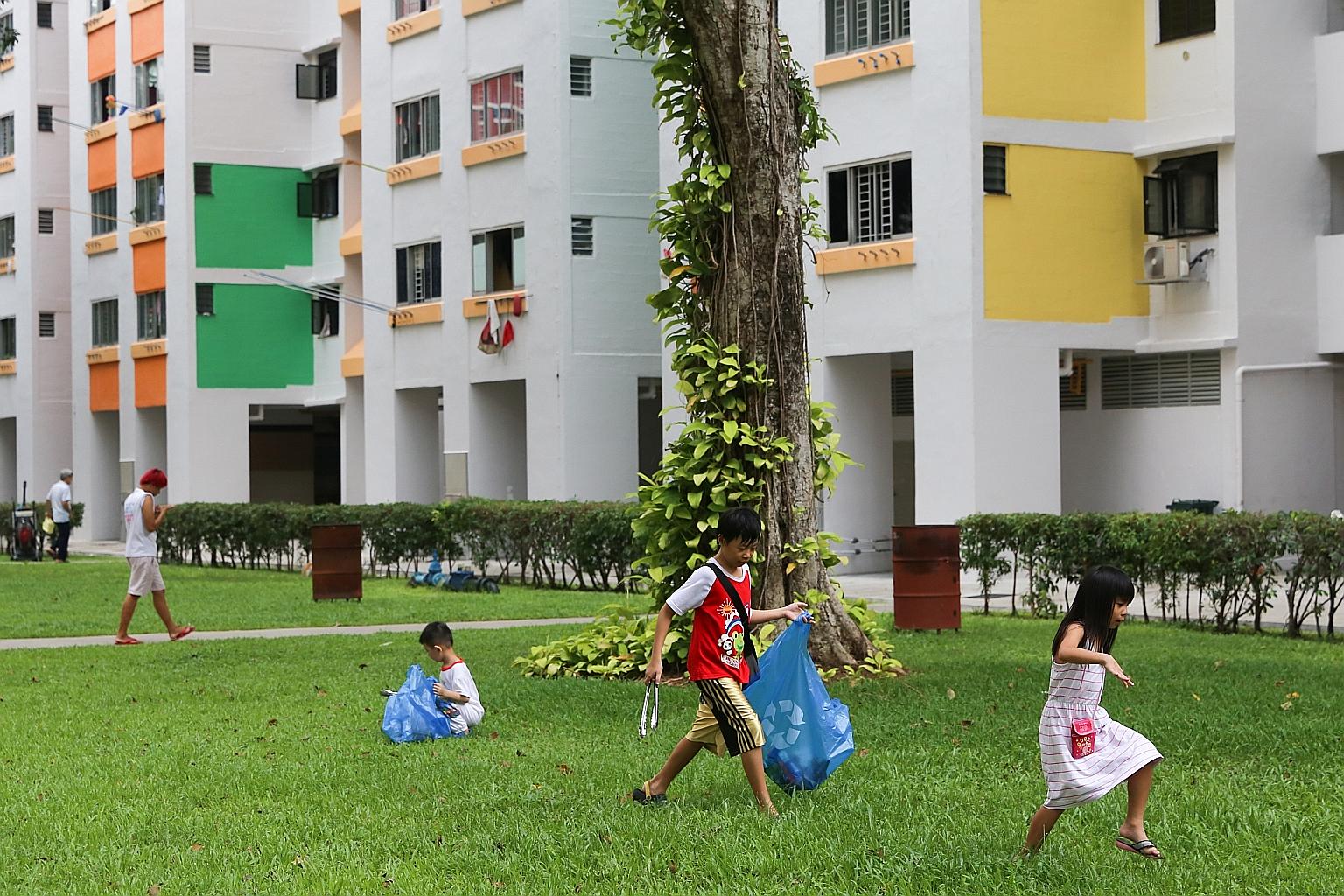 Five-year-old Melissa Choo (right) joining her brother, nine-year-old Choo Yong Sheng (in red), in the mass clean-up in Henderson Heights yesterday. All in, about 150 children took part in the event.