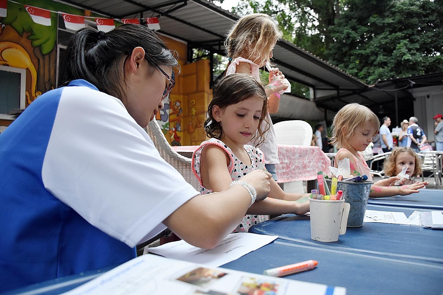 Children getting their arms painted yesterday at the farmers' market in Loewen Road. Melbourne Specialist International School set up a booth there selling cards and bookmarks made by its students to raise funds to build a covered walkway between the