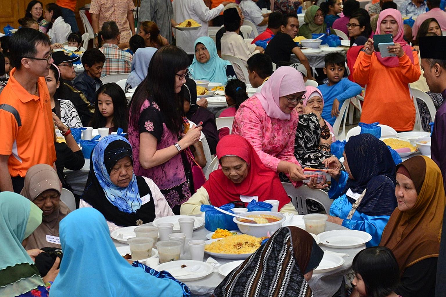 Speaker of Parliament and Marsiling-Yew Tee GRC MP, Madam Halimah, distributing cash and vouchers to needy Marsiling residents at a breaking-of-fast session held at Marsiling Community Club yesterday.