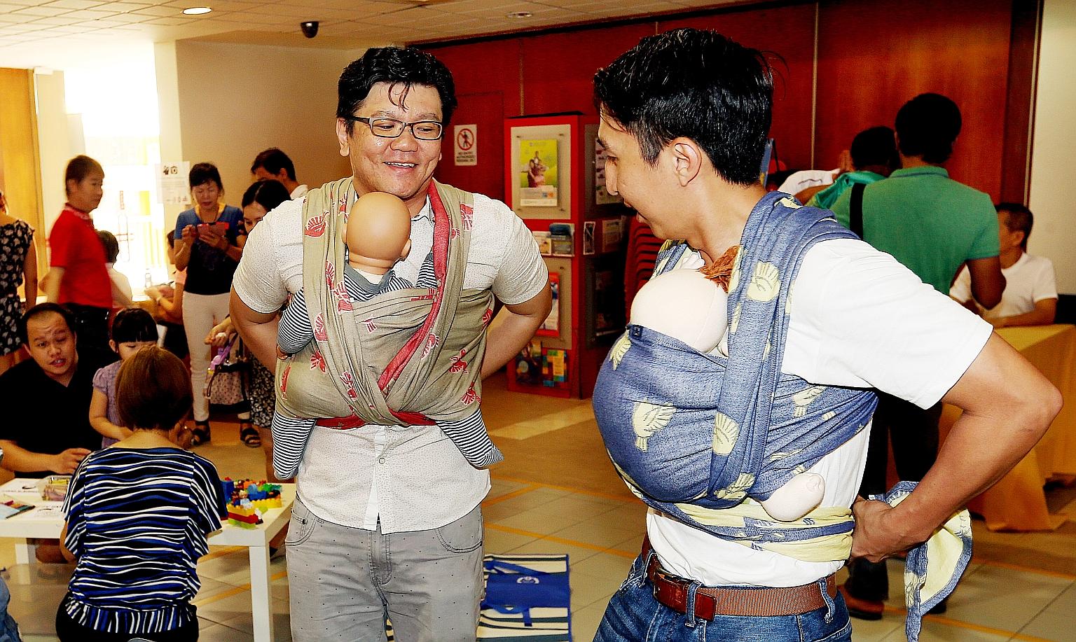 Fathers practising baby-wearing, first with dolls, before carrying their own babies, at Henderson CC yesterday. It was part of a Father's Day baby show held ahead of the actual occasion next Sunday.