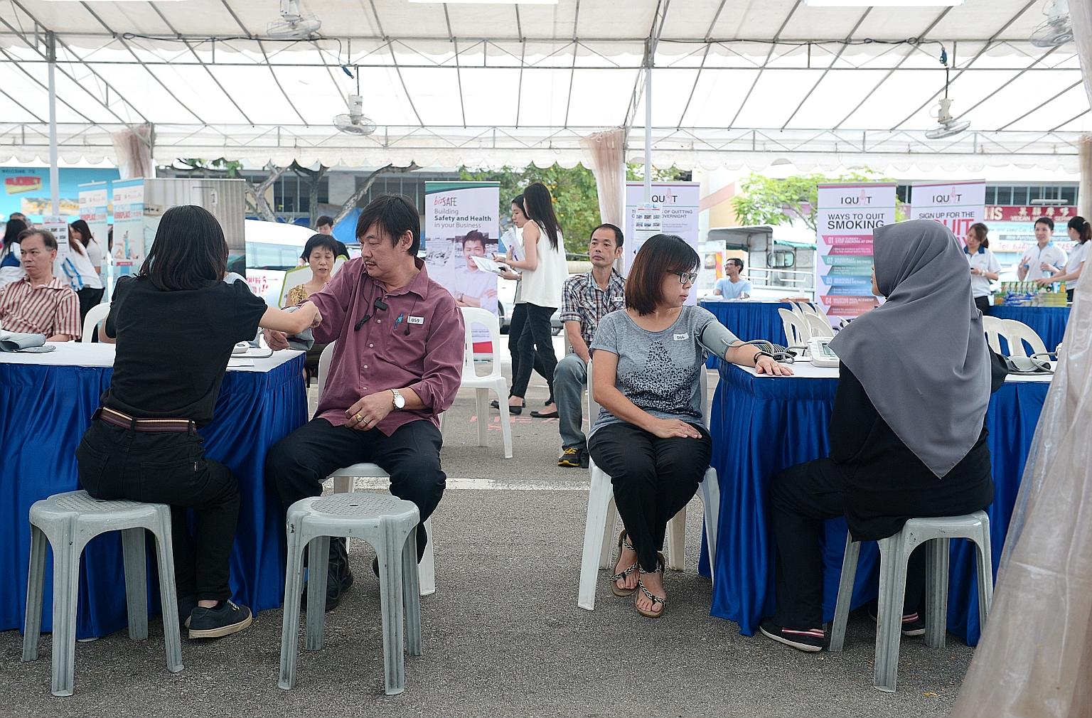 Workers taking advantage of a free medical check-up in a pop-up tent at Tampines Industrial Park A, organised by HPB as part of the Healthy Workplace Ecosystem initiative.