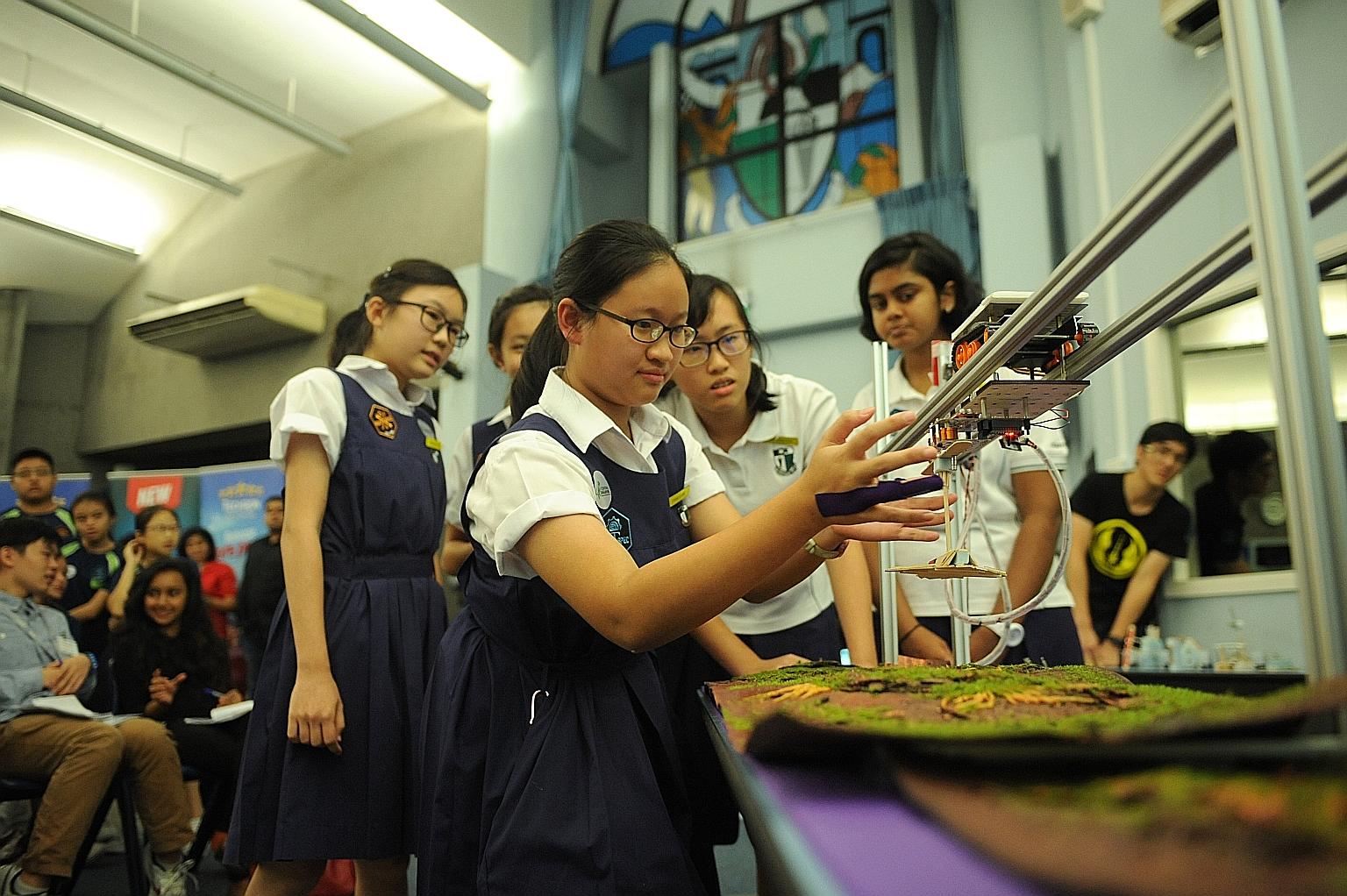 Chang Li-Ann from Raffles Girls' School testing her team's prototype, the V-Wing Fighter, with her teammates looking on. They were among the 240 students involved in a competition under the Fuel Your School - Stem @ Central Singapore initiative held 