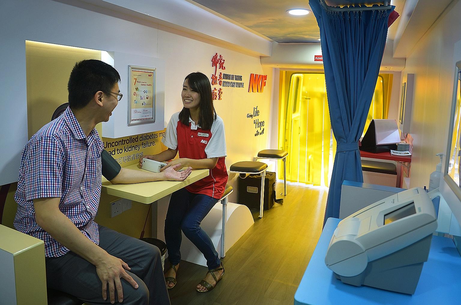 Ms Audrey Ngo, an outreach executive of NKF, checking blood pressure during a consultation session aboard the Diabetes Health Bus.