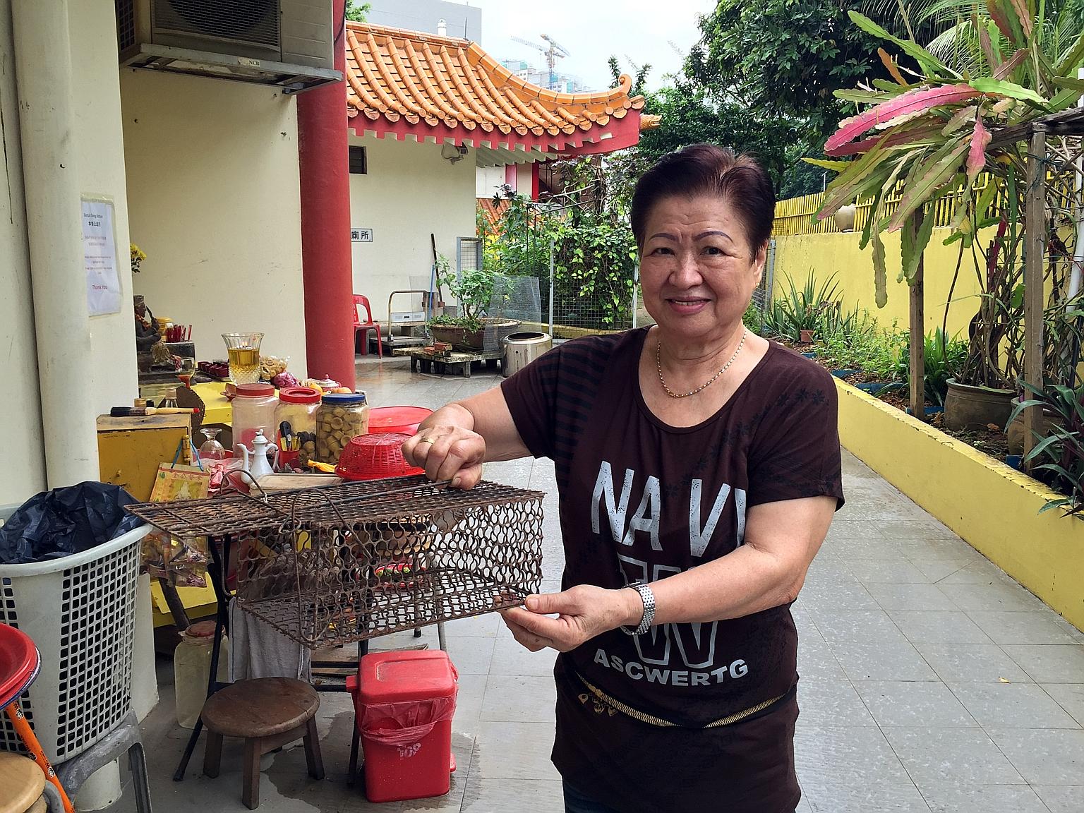 Ms Sim holding a metal cage with cuttlefish bait used to trap rats. The situation has improved from three months ago, though temple staff and volunteers still see "one or two small rats occasionally".