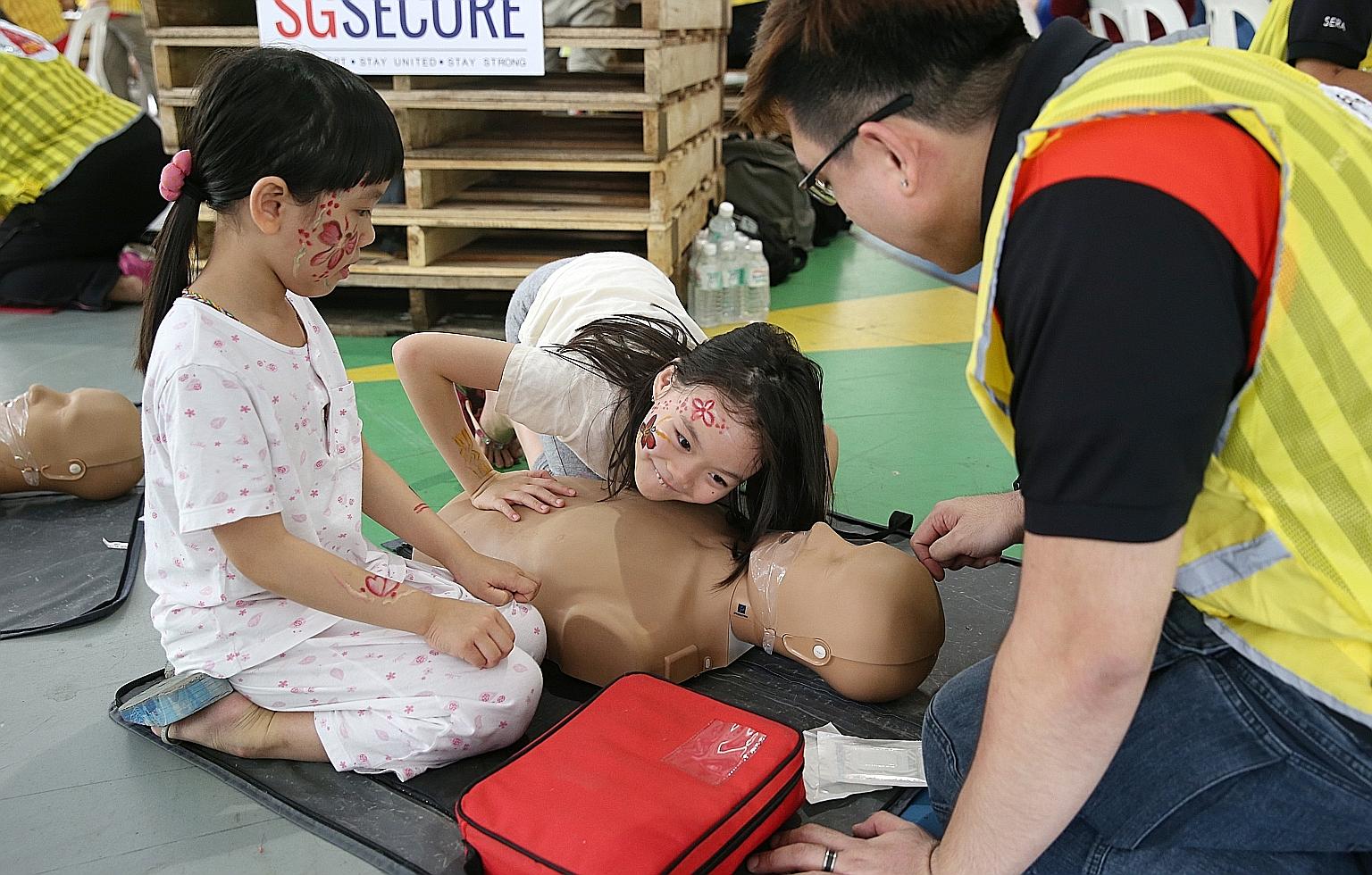 Sisters (from left) Quek Gek Ling, six, and Quek Gek Boon, eight, learning about CPR from a member of the Community Emergency Response Team, Mr Adris Chong, 31, at the Our Blocks Rock event in Hougang yesterday.