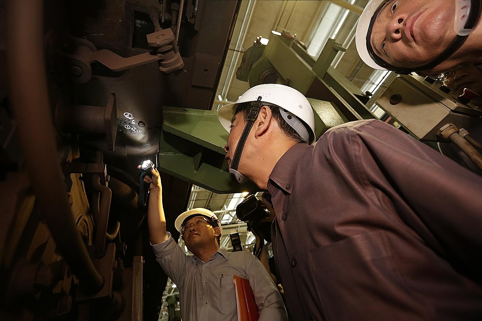 Mr Khaw (centre) being shown a hairline crack on the car-body bolster of a train at Bishan depot yesterday. Also present was Mr Sitoh Yih Pin (right), who chairs the Government Parliamentary Committee for Transport. Based on investigations, the crack