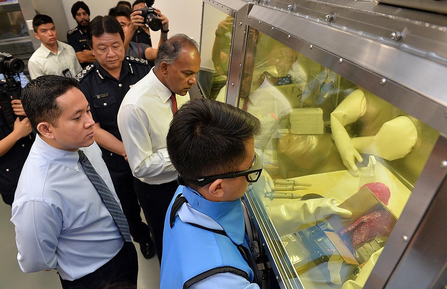 Mr Shanmugam touring the Radioactive and Nuclear Analysis Laboratory yesterday with (from left) Parliamentary Secretary Amrin Amin and ICA Commissioner Clarence Yeo. The lab is part of the Protective, Analytical and Assessment Facility in Pasir Panja