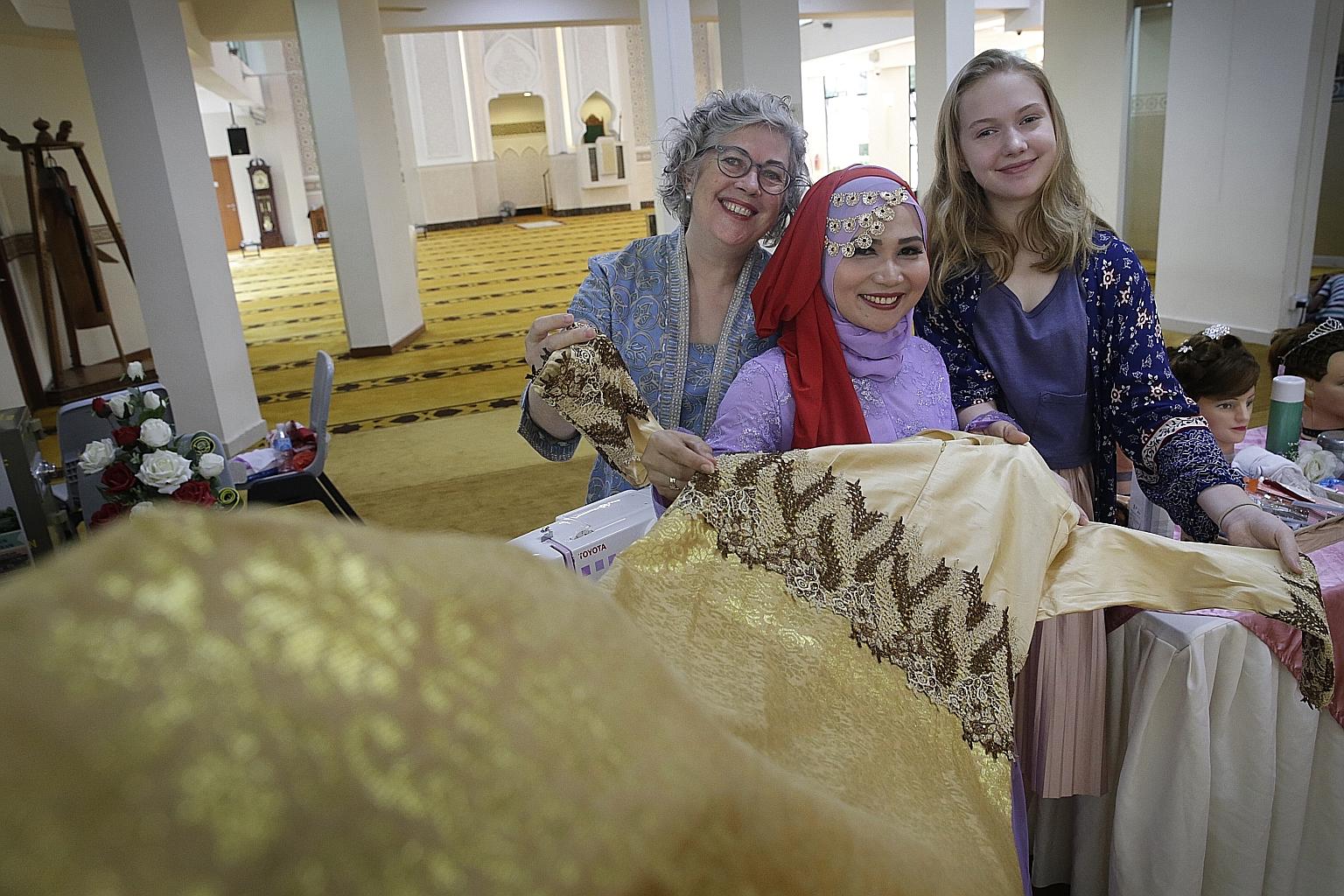 Ms Asih (centre), Prof Jacobs (left) and her daughter Loreilei Cairns, with a dress made by Ms Asih's sewing-class teacher.