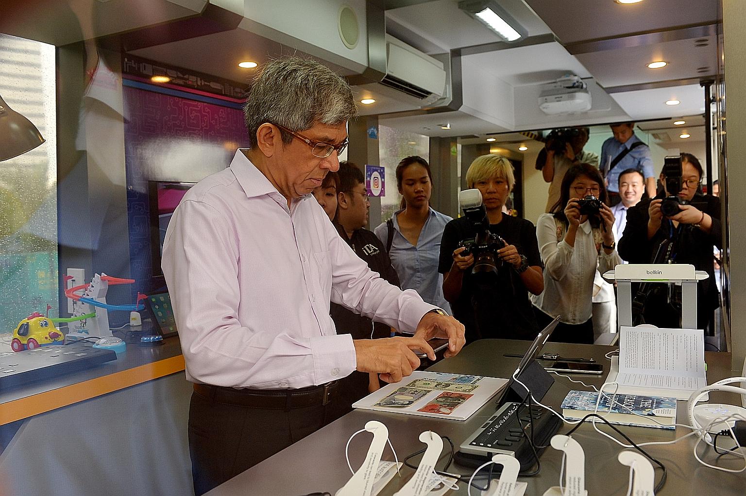 Dr Yaacob trying a money reader app yesterday inside the mobile IDA Lab at the E² Connect forum and exhibition.