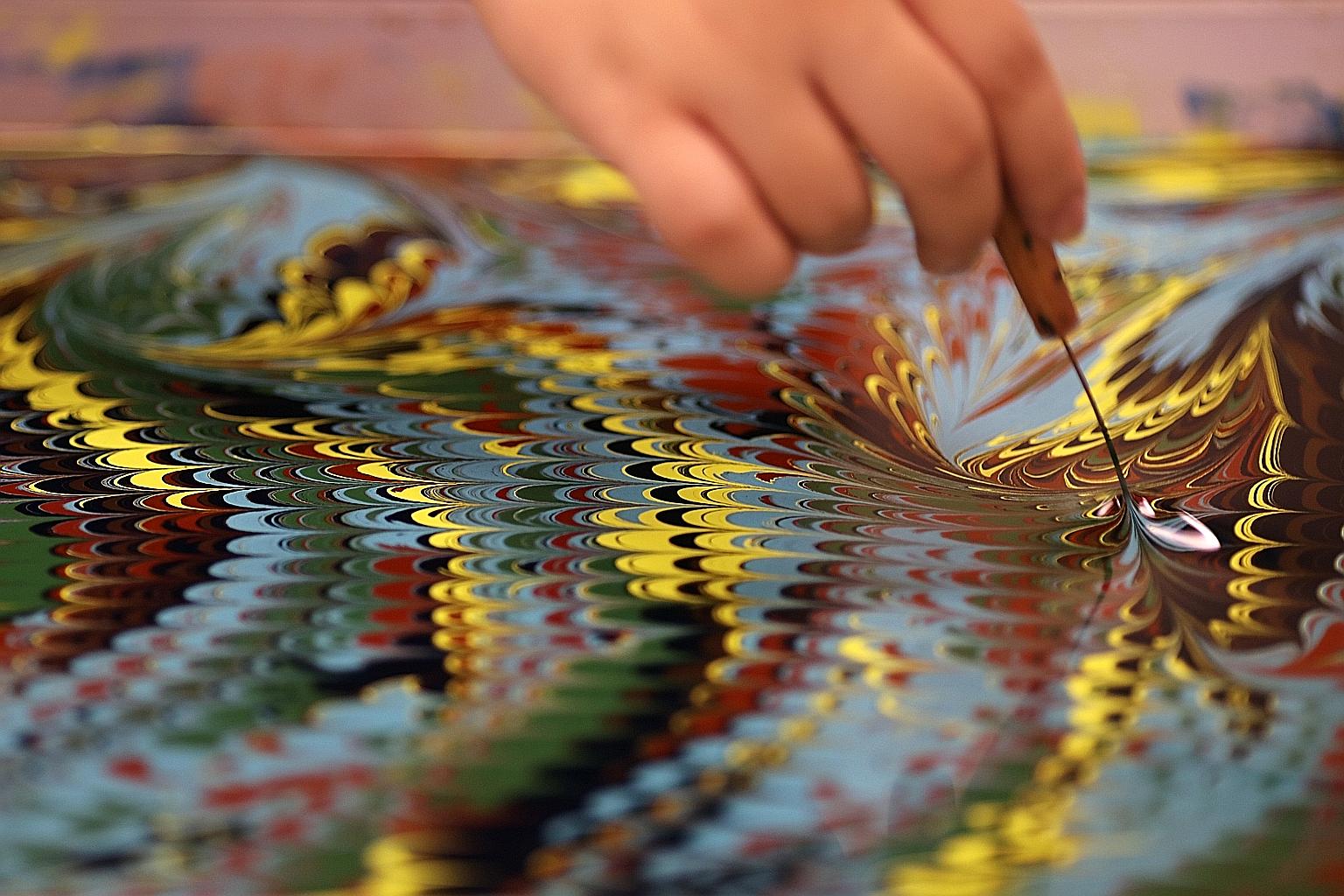 Turkish visual artist Garip Ay demonstrating one of the oldest forms of painting from Turkey known as Ebru. A pattern emerges after a fine wire comb is "dragged" on a paint-coated surface of water. The pattern is then printed by floating a sheet of p