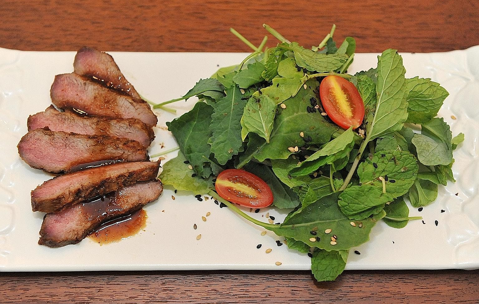 The grilled meat is served with bitter salad leaves to balance out the sweetness of the meat.