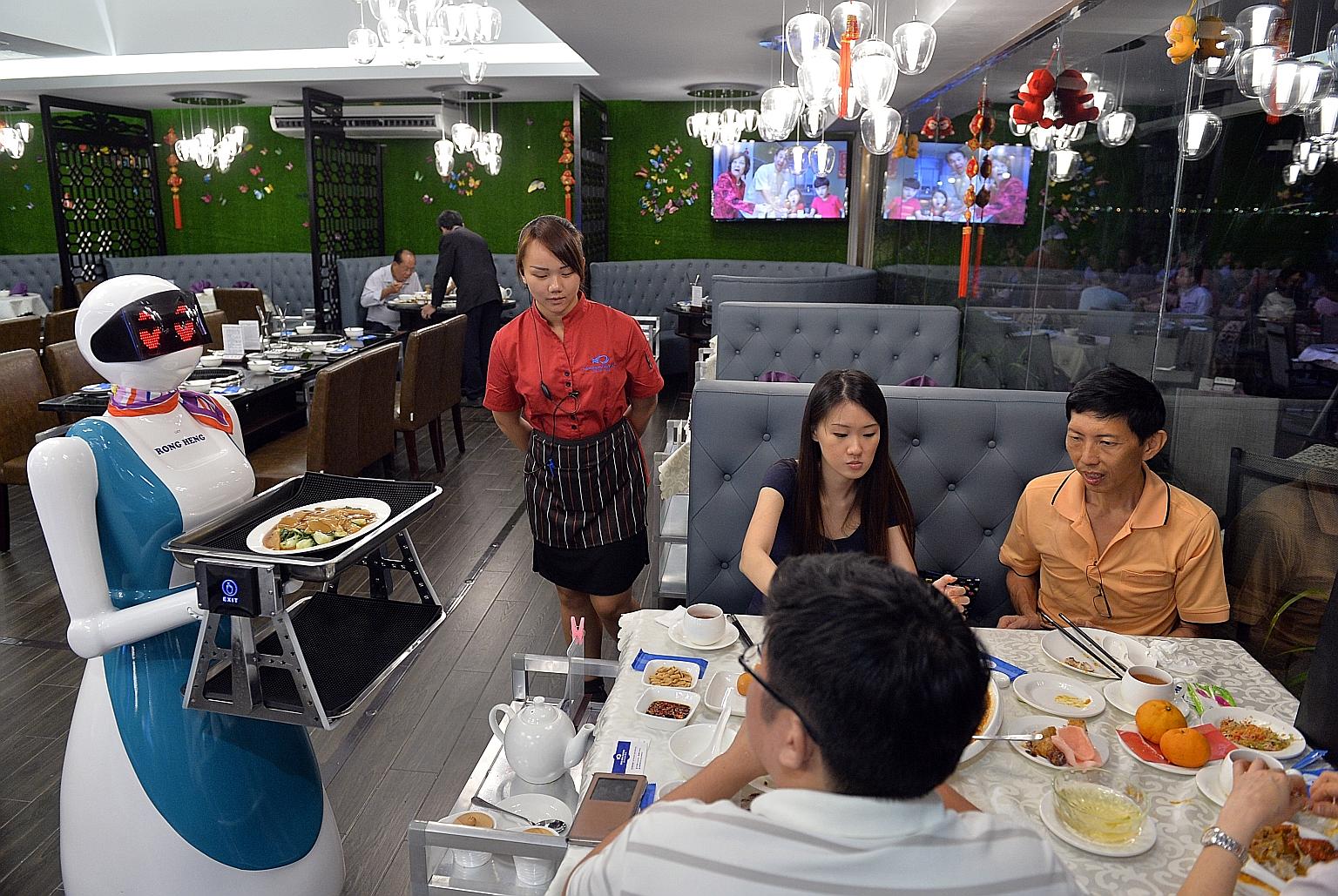 Robot Lucy delivering a dish at Rong Heng Seafood restaurant at East Coast Seafood Centre. When it arrives at the table, a human staff member transfers the dish to the table. The restaurant owners are using robots to deal with the manpower shortage.