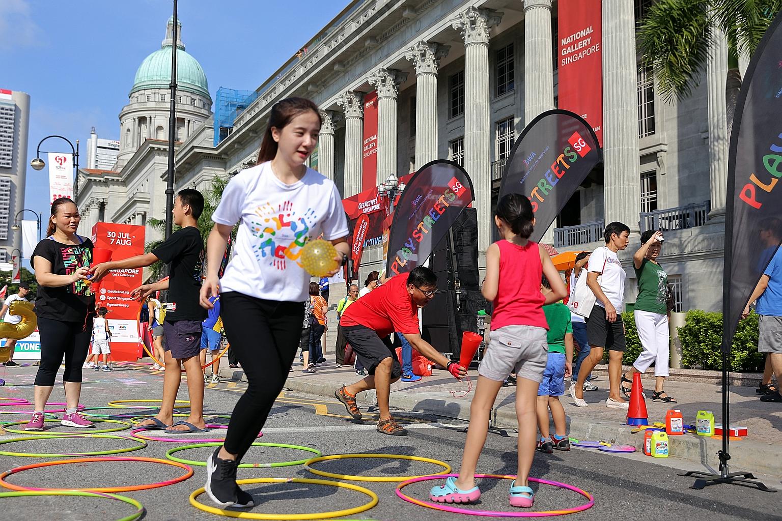 Singapore Wellness Association volunteers Damiel Ang (in black), 14, and Poh Wen Lin (in white, foreground), 19, facilitating street games in front of the National Gallery Singapore yesterday as part of the activities during the GetActive! Singapore