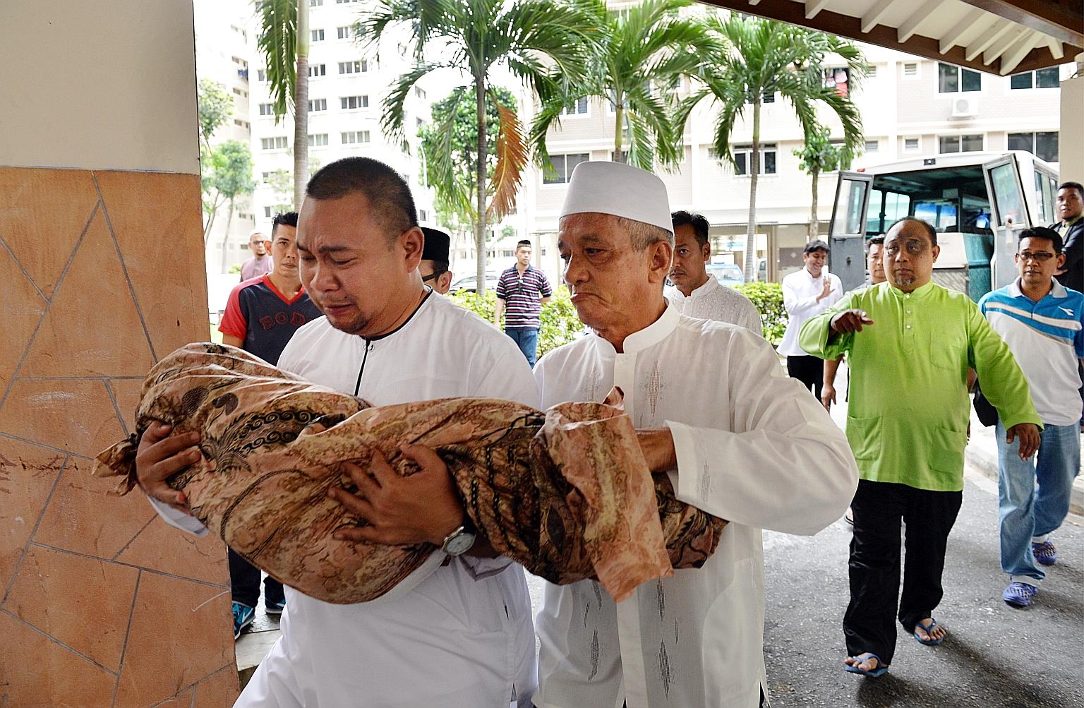 Mr Syahrom Mohammad Yunus carrying the body of his daughter for burial on Feb 14. Three-year-old Nur died of pneumonia following the traumatic injury to her head in the fall.