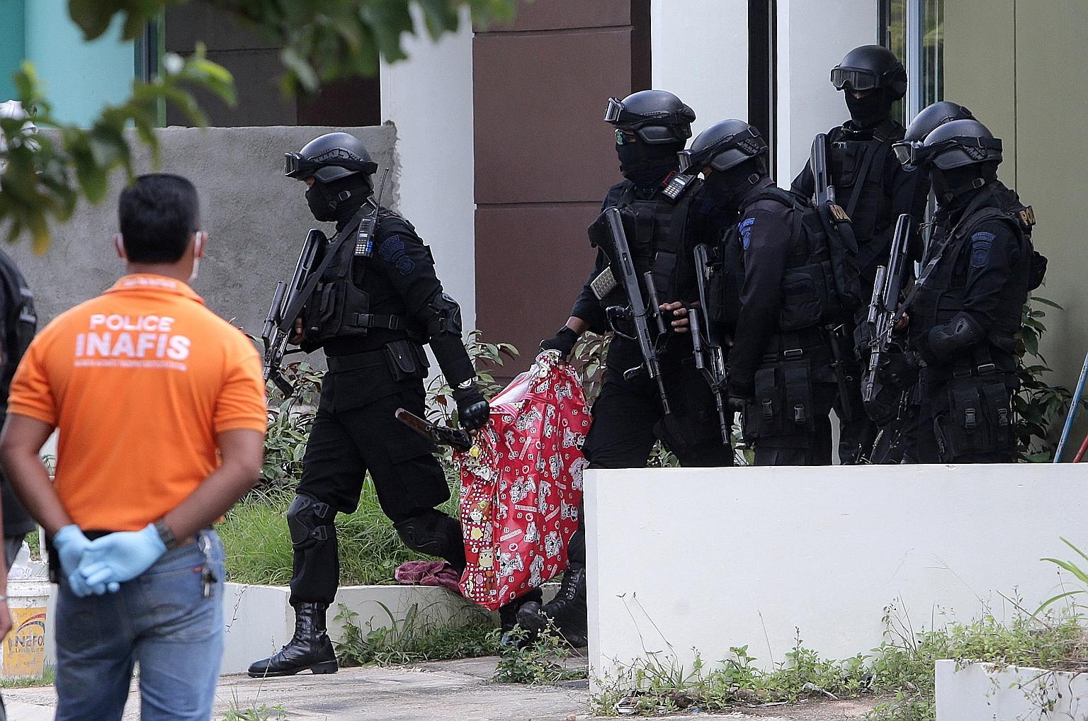 Indonesian anti-terror police with a bag containing a suspected firearm and other evidence taken from a building during yesterday's raid in Batam, where six members of the militant cell were arrested. Singapore's security agencies and their Indonesia