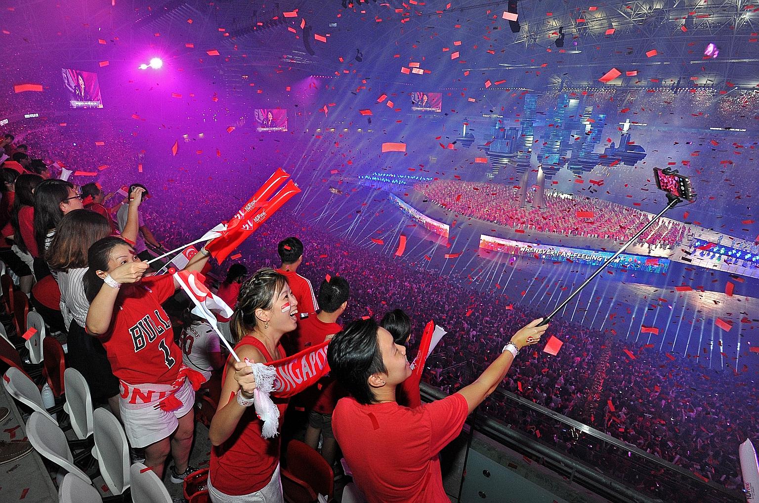 Parade-goers capturing the moment as the crowd sings Home at the finale of the parade, the first held in Kallang in a decade. Some 150 special-needs participants led the 55,000 spectators in hand-signing along to the songs.