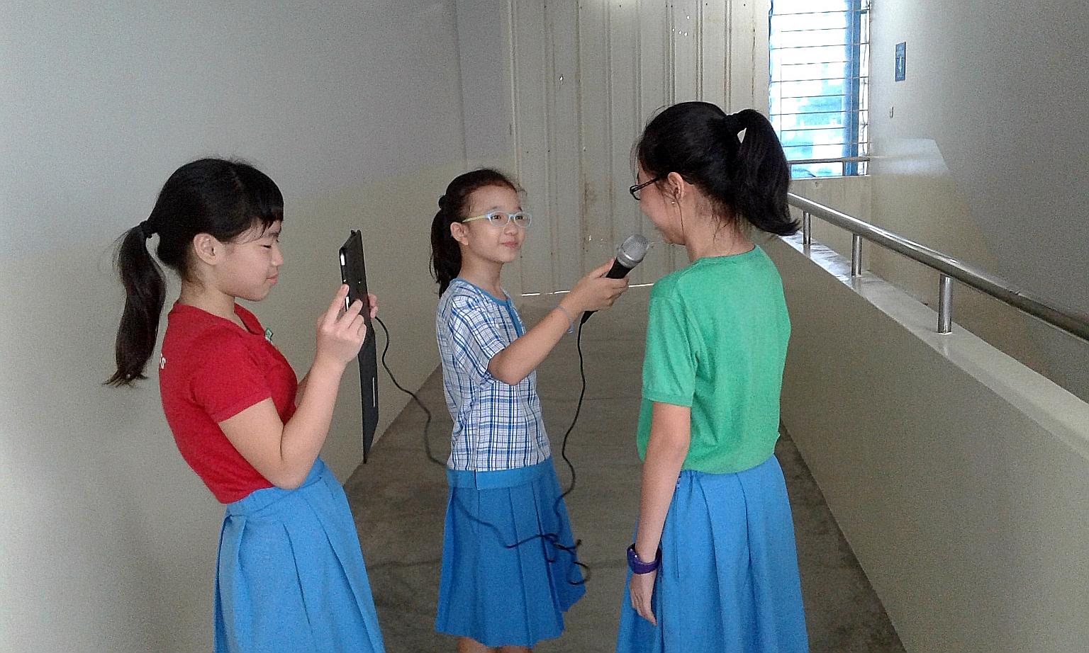 Two Jiemin Primary pupils, armed with a microphone and an iPad, interviewing a schoolmate.
