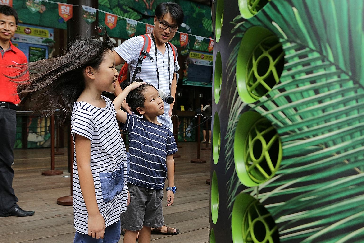 Steffi Teo, eight, and her brother, Leroy, six, enjoying the breeze from the Airbitat Smart Cooler. With them is their father, Mr Steven Teo, 38. If the trial at the zoo's ticketing area is successful, cool zones will be set up at all four wildlife p