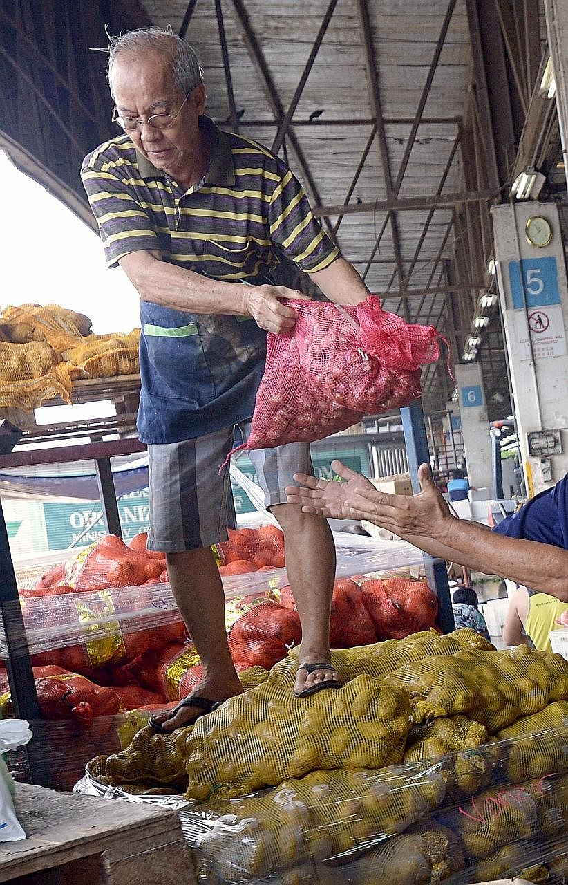 Vegetable importer Lim Hiok Chuan, 65, hands out sacks of potatoes to an employee of Willing Hearts at the Pasir Panjang Wholesale Centre. Mr Lim, who has been giving his products to Willing Hearts regularly for the last 10 years, has never turned do