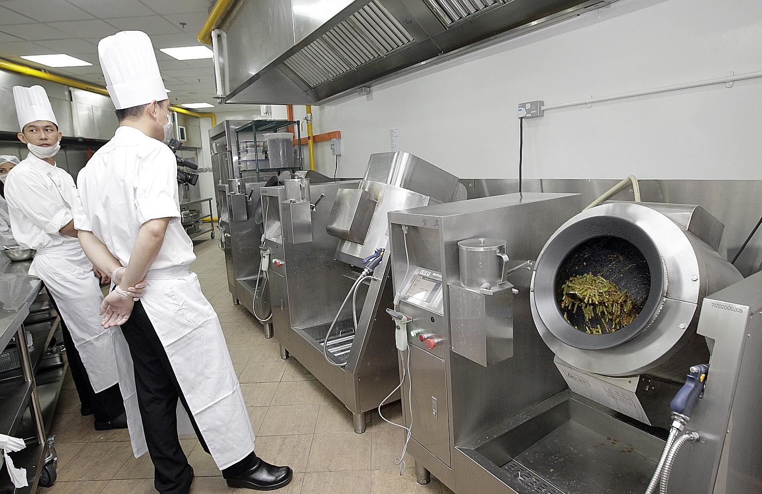 Chefs waiting for a cooking robot to finish its work at a Tung Lok outlet. Tung Lok executive chairman Andrew Tjioe says it takes just one person to operate two robotic cooking machines that can cook 60kg of food for the restaurant chain.