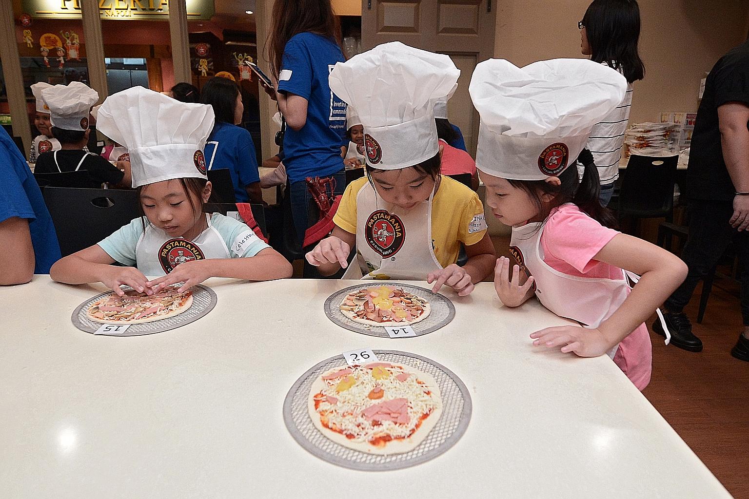 It was a pizza extravaganza for pupils (from left) Celestine Lim, nine, and sisters Elina Kong, nine, and Sririta Kong, seven, yesterday. The three girls were among 34 beneficiaries of The Straits Times School Pocket Money Fund invited to a pizza-mak