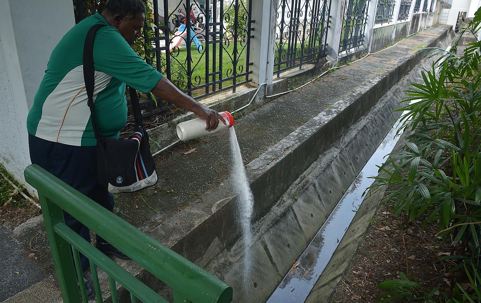 National Environment Agency officers putting granular pesticides in stagnant water in Siglap on Thursday. Ministers Gan Kim Yong and Masagos Zulkifli will speak on the spread of Zika when Parliament sits on Tuesday.
